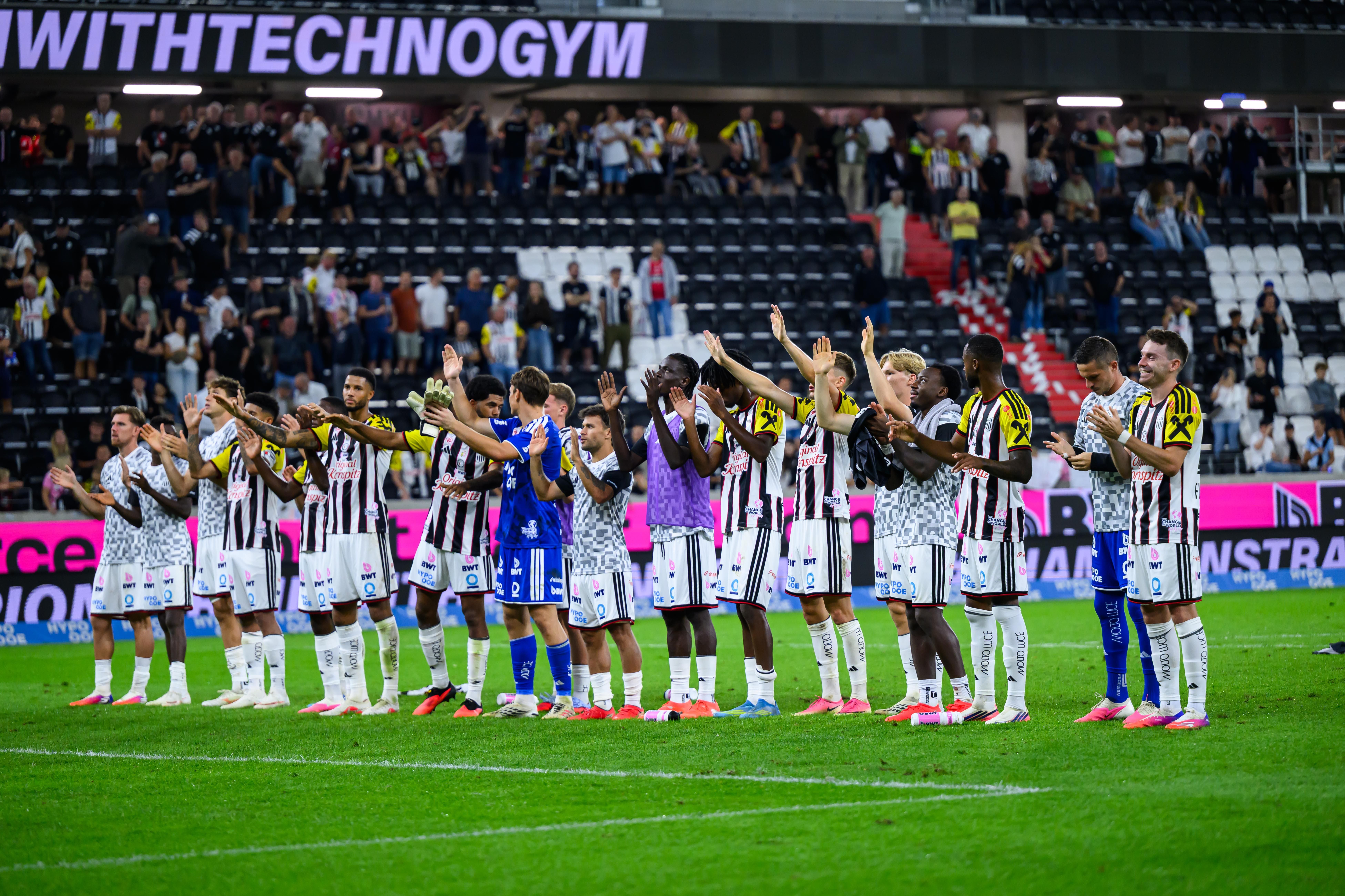 Fußballspieler des LASK jubeln im Stadion und applaudieren den Fans auf den Rängen.