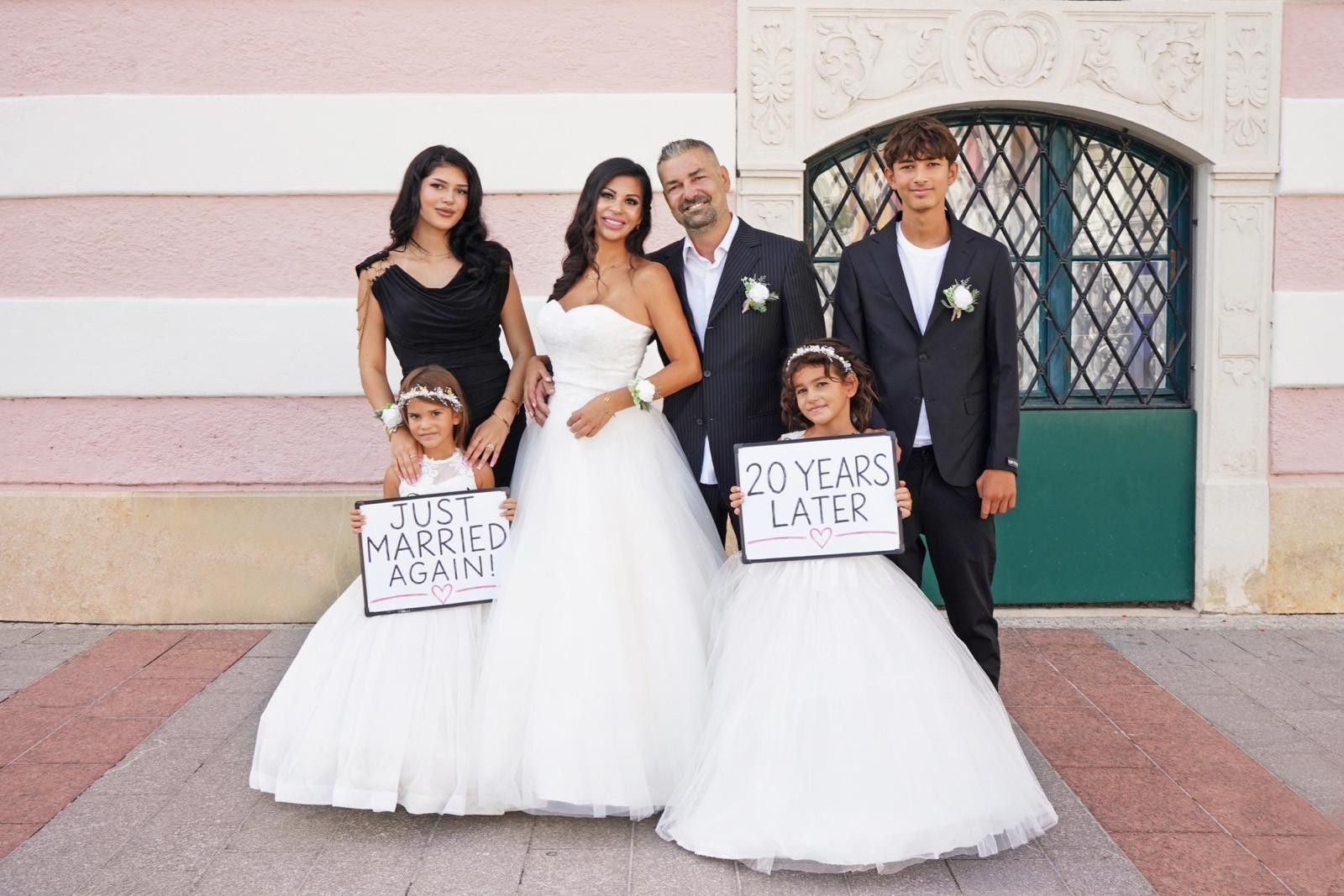 Eine Familie posiert zur Hochzeit; zwei Kinder halten Schilder mit Jahrestexten in den Händen.