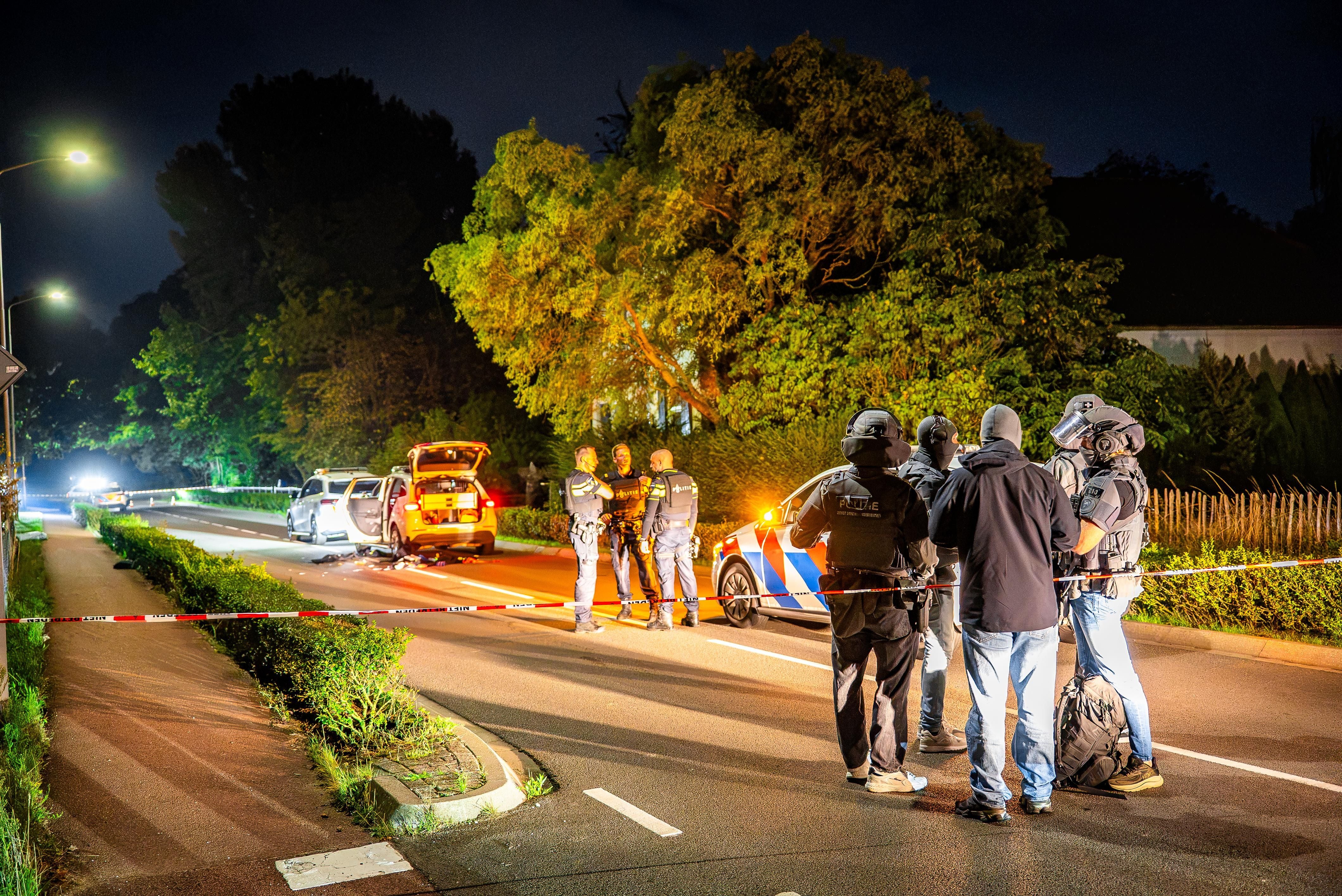 Polizisten und Ermittler untersuchen nachts einen abgesperrten Tatort nach einer Schießerei.