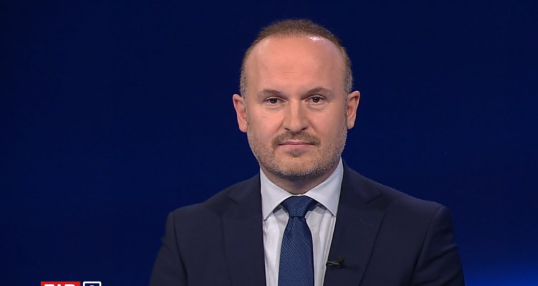 Ein Mann im Anzug sitzt vor blauem Hintergrund im Studio der Nachrichtensendung ZiB2.