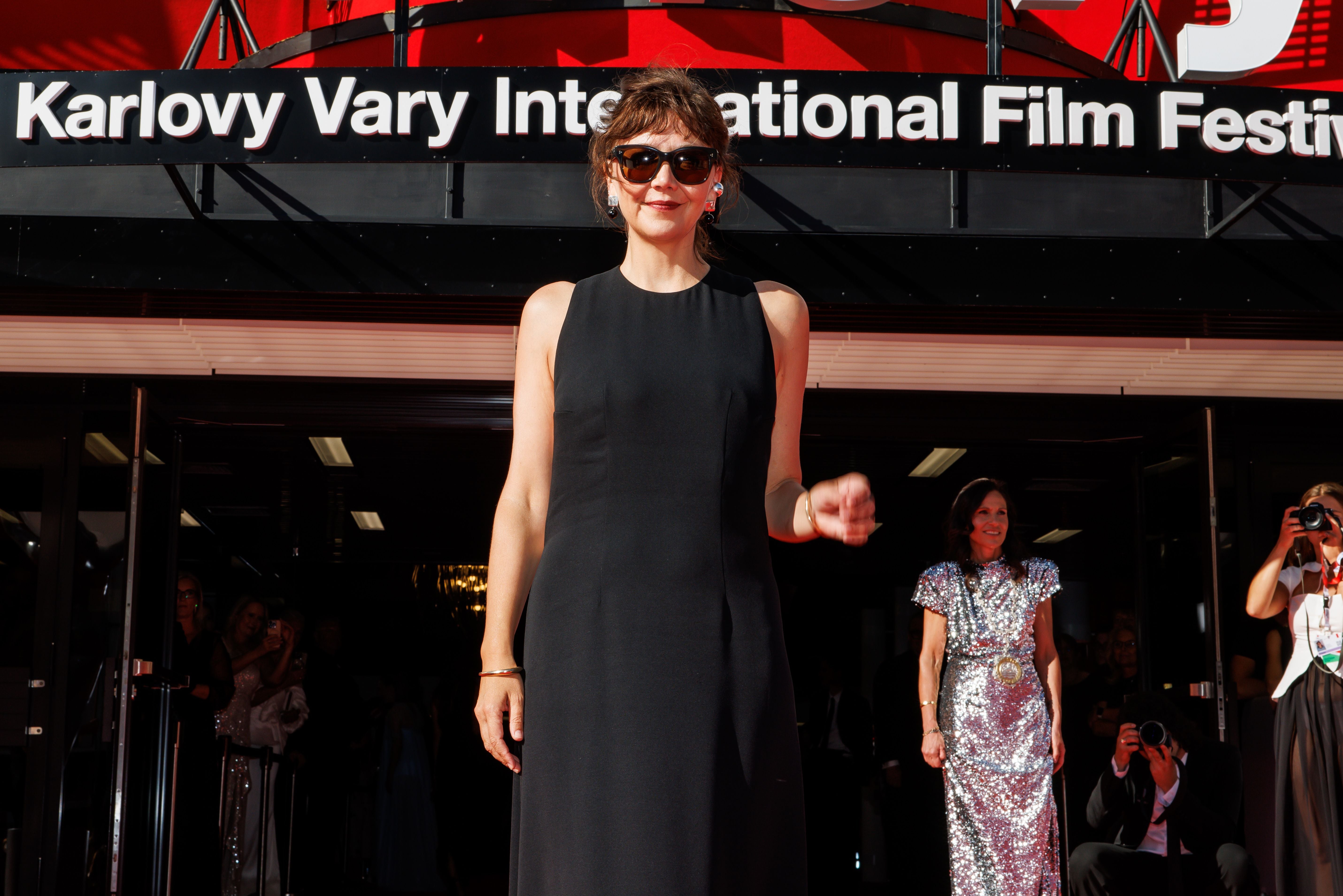 Frau in schwarzem Kleid mit Sonnenbrille steht vor dem Eingang eines Filmfestivals.