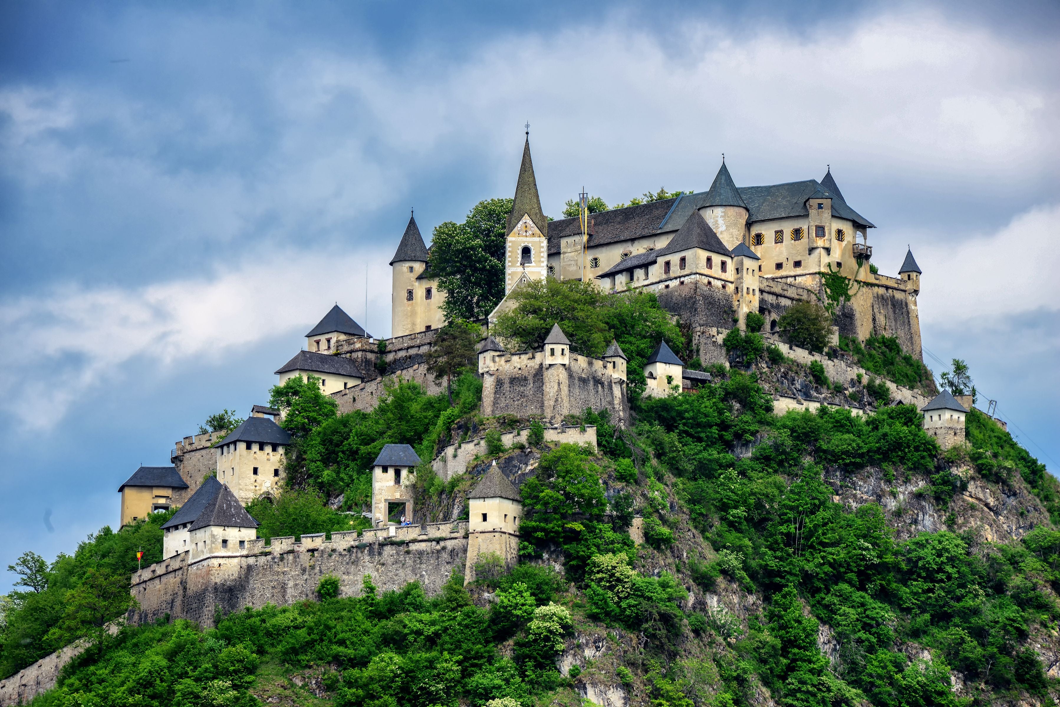 Burg Hochosterwitz thront auf einem bewaldeten Hügel unter bewölktem Himmel in Kärnten, Österreich.