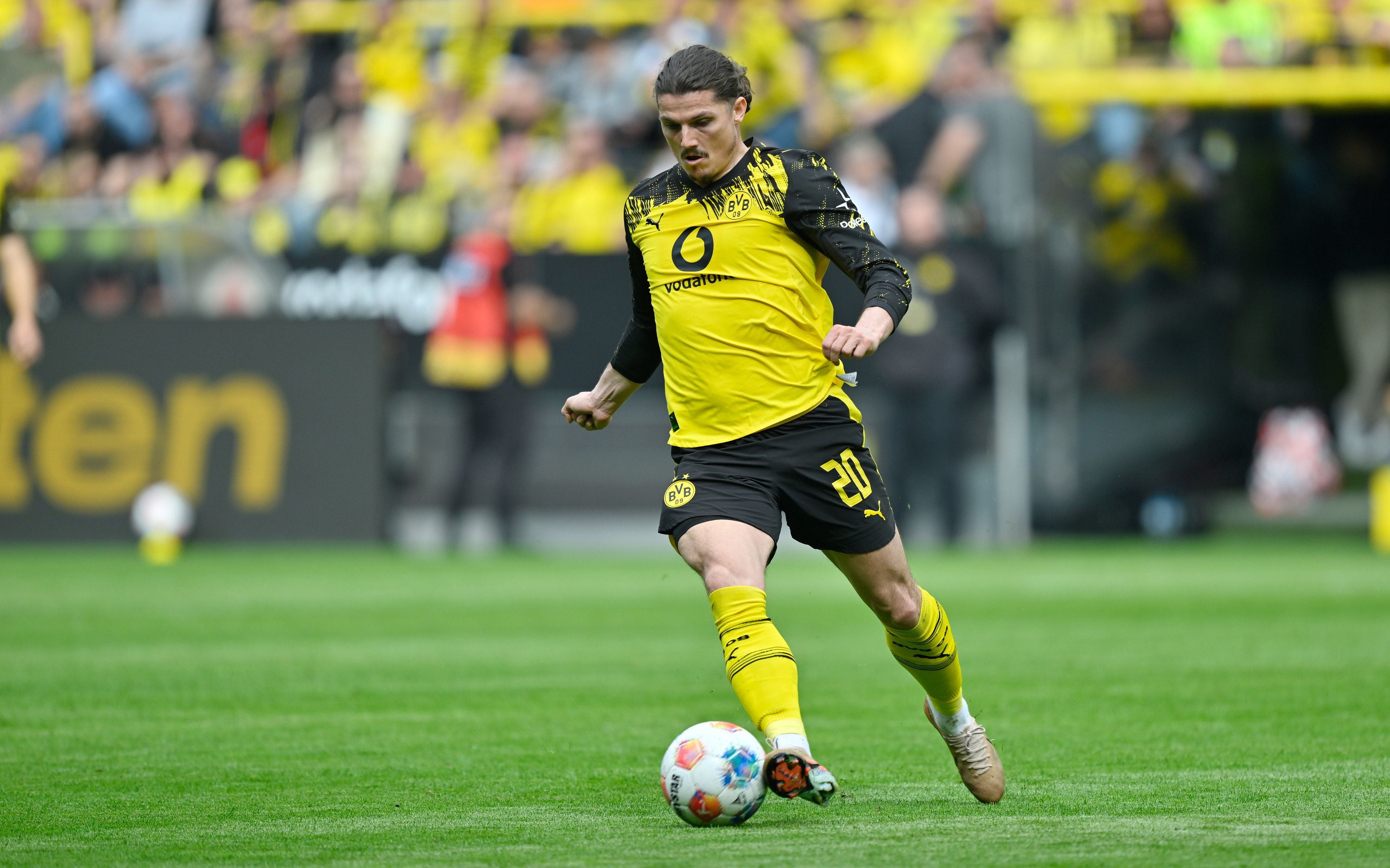 Ein Borussia Dortmund-Spieler mit der Nummer 20 spielt den Ball auf dem Fußballfeld.
