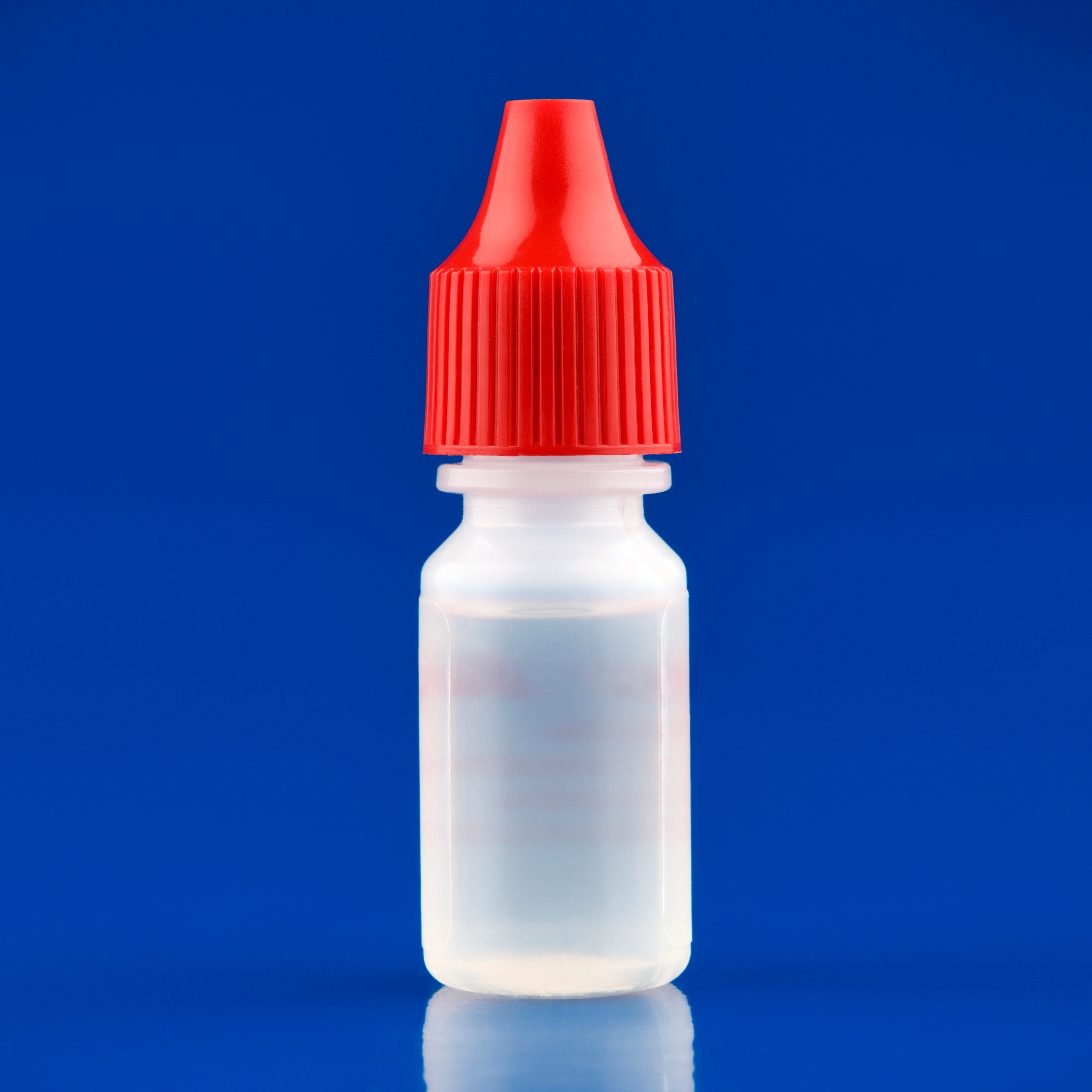 Kunststoffflasche mit roten Deckel, vermutlich für Augentropfen, auf blauem Hintergrund.