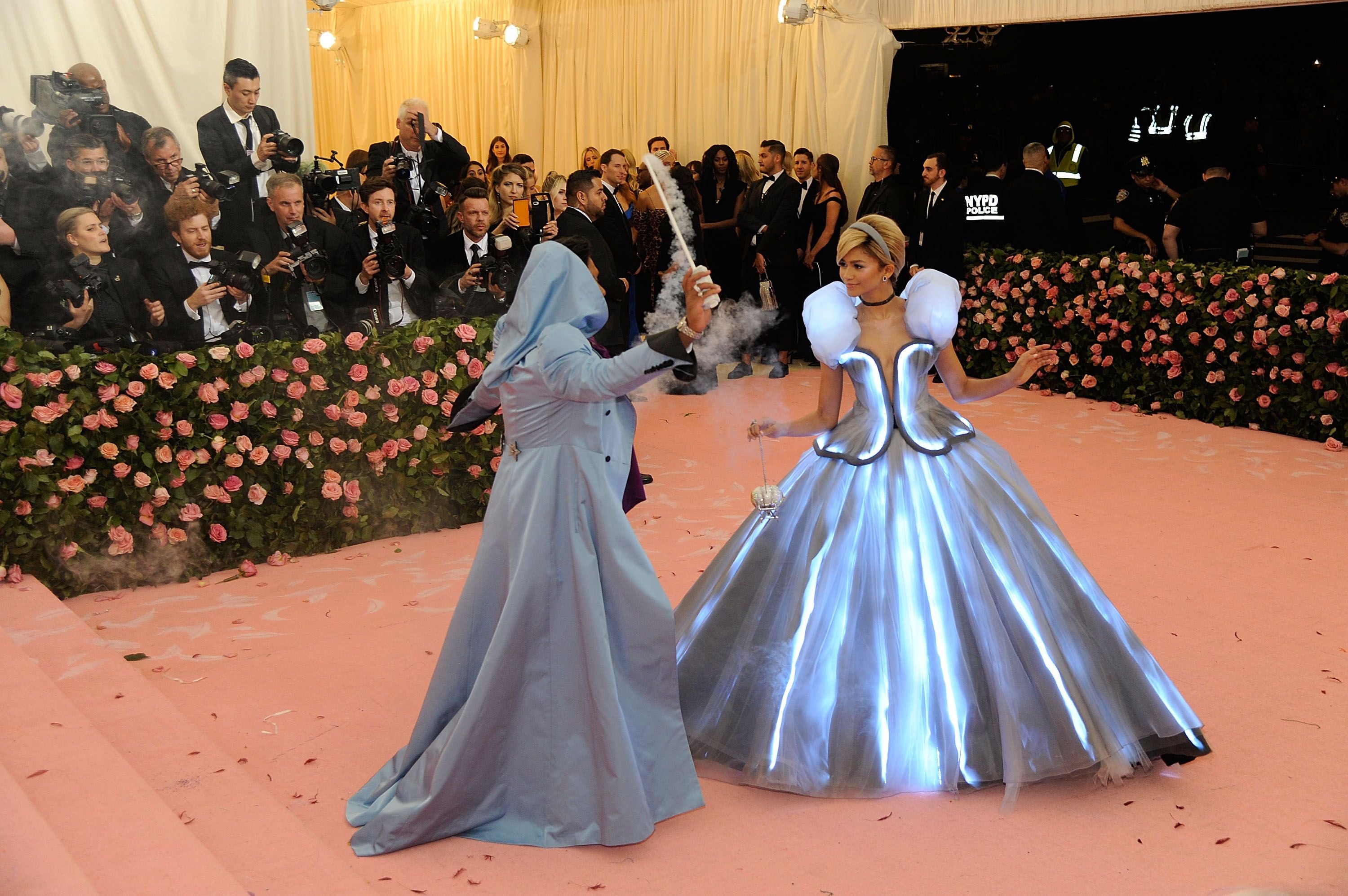Zwei Personen in märchenhaften Outfits posieren auf dem pinken Teppich der Met Gala 2019.