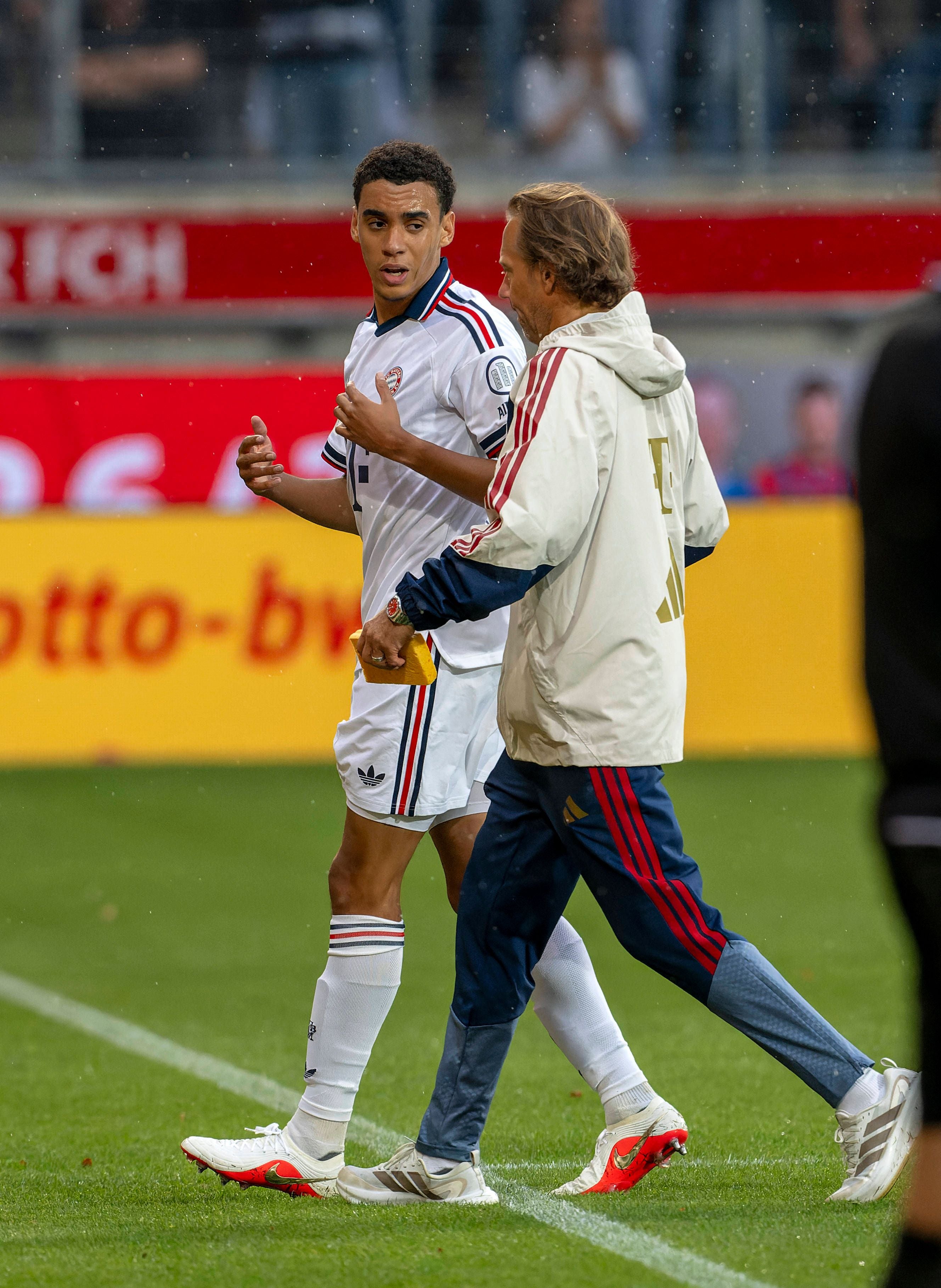 Jamal Musiala wird nach einem Zusammenbruch vom Mannschaftsarzt vom Spielfeld geführt.