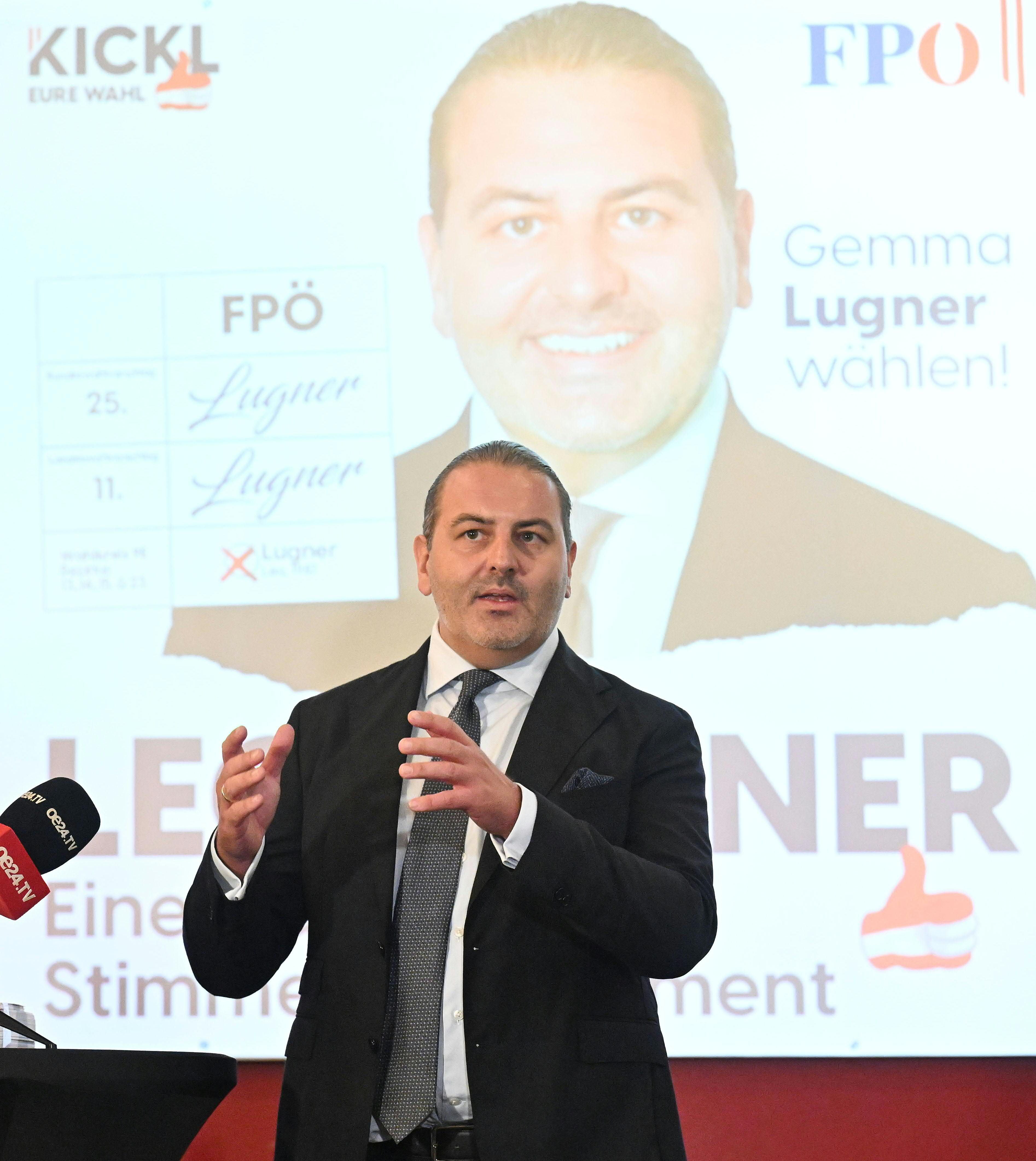 Ein Mann im Anzug spricht bei einer Präsentation vor einem Wahlplakat der FPÖ.