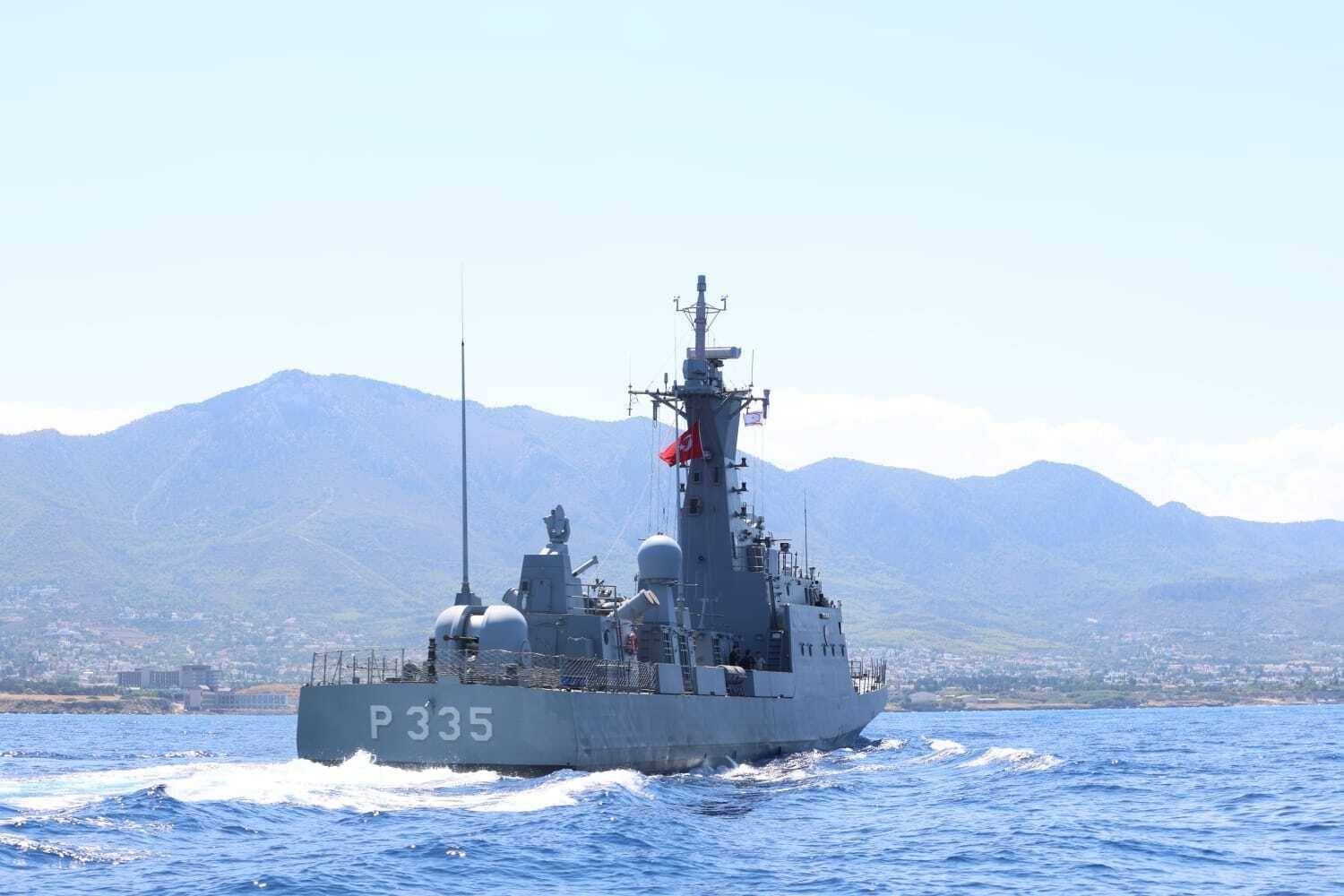 Ein Marineschiff mit der Nummer P335 fährt nahe der Küste von Kyrenia, Berge im Hintergrund.