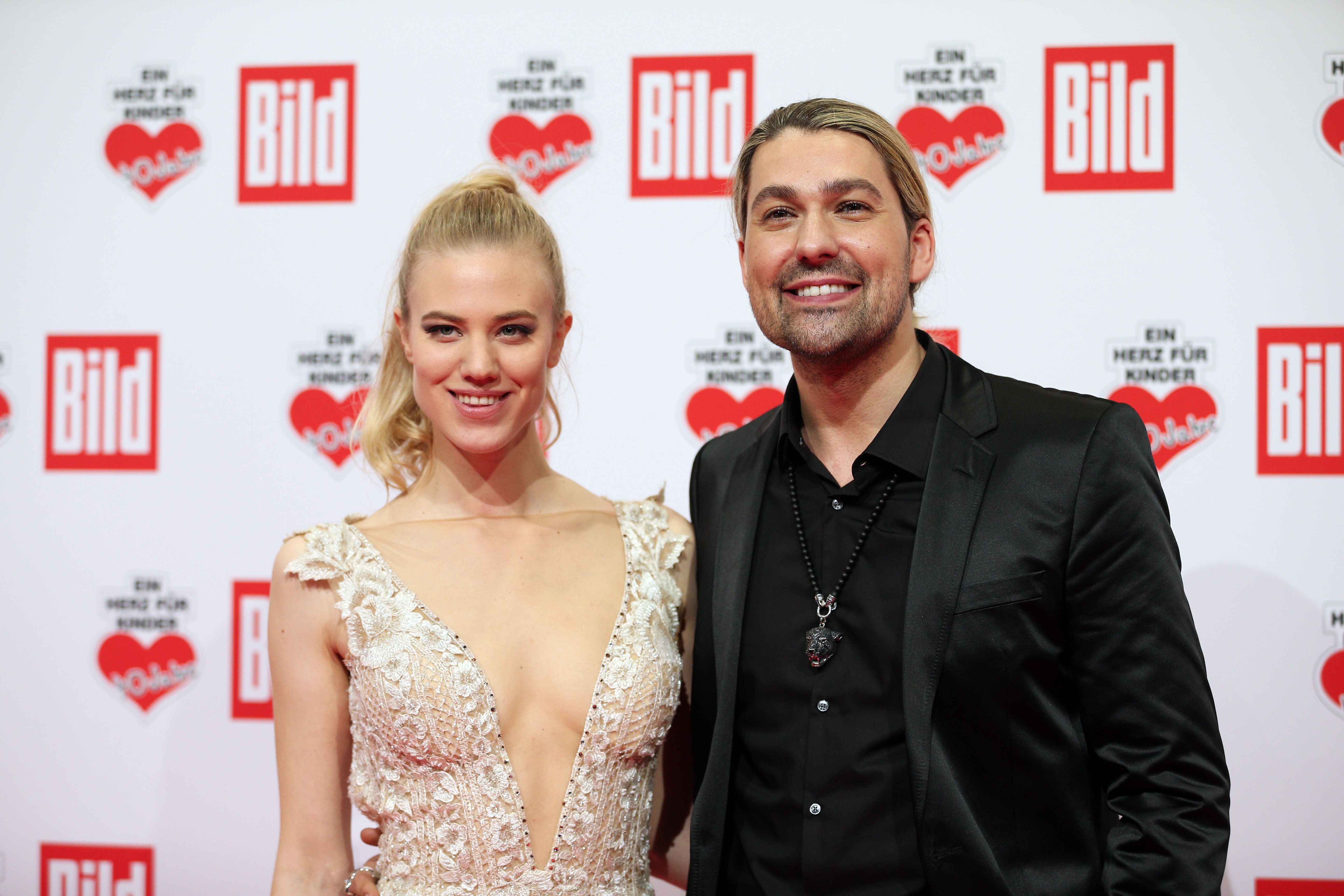Ein Mann und eine Frau posieren elegant auf dem roten Teppich bei einer Gala in Berlin.