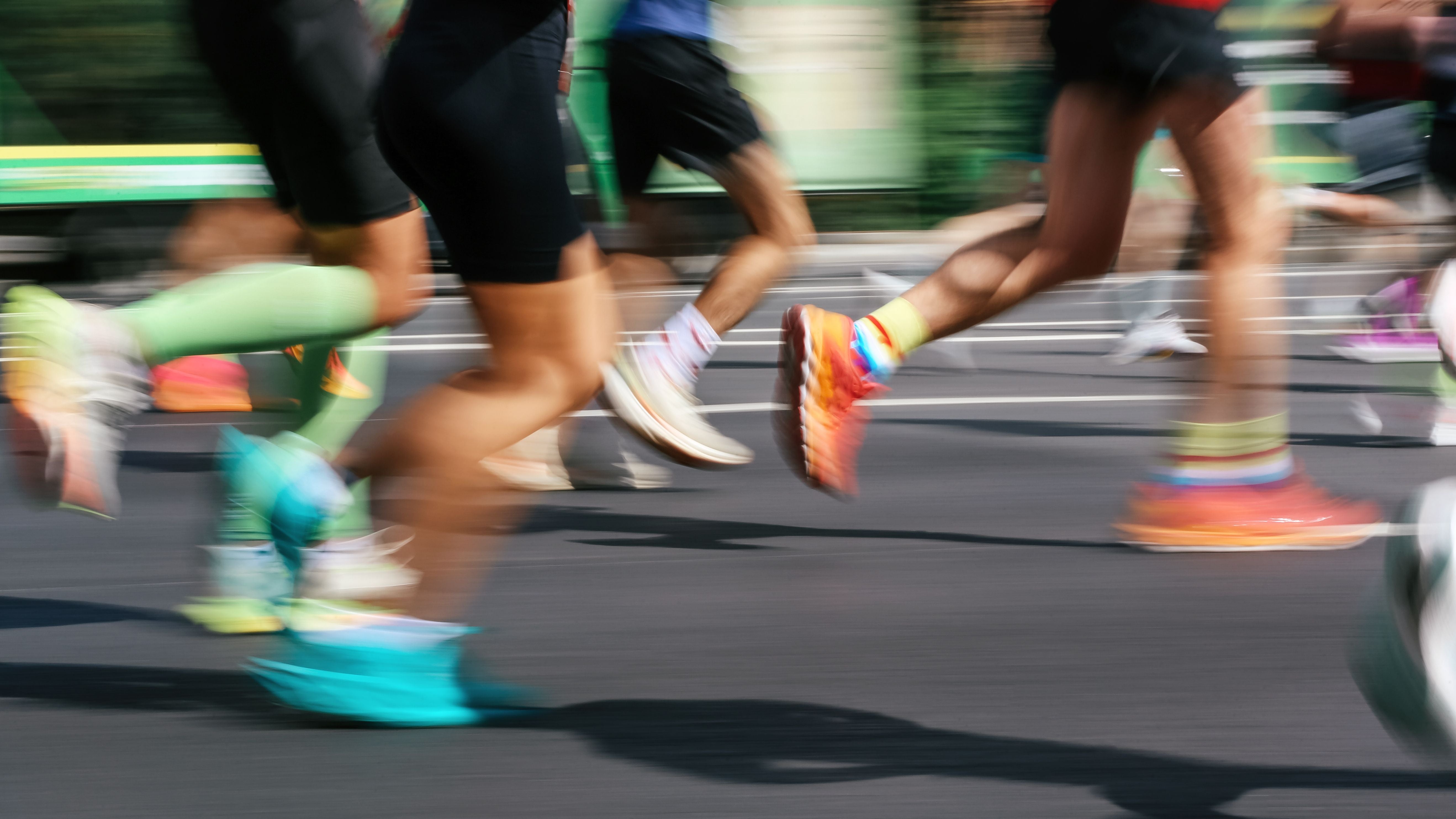 Bewegungsunscharfe Aufnahme von Läuferbeinen bei einem Stadtmarathon auf Asphalt.