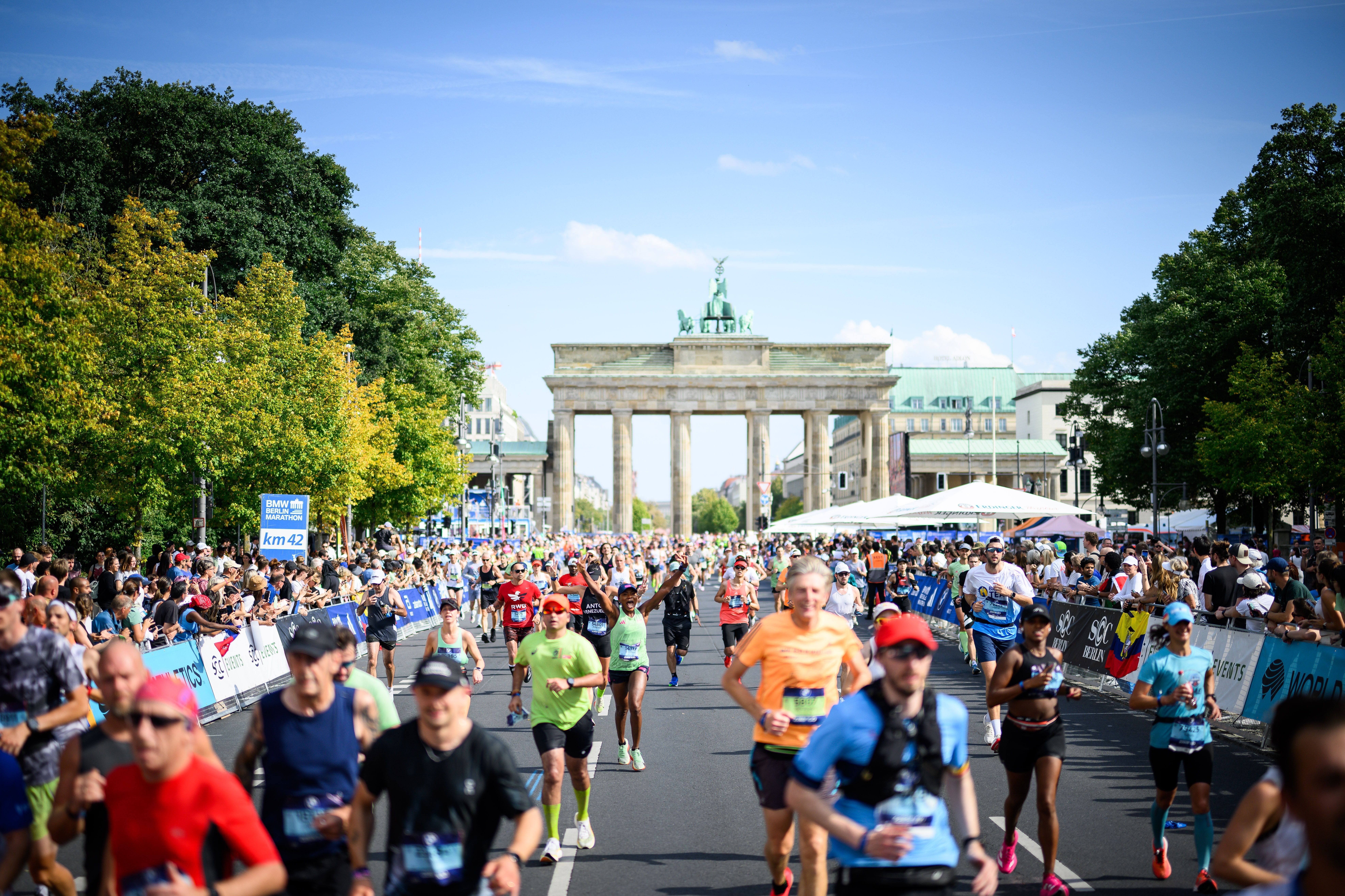 Läufer passieren das Brandenburger Tor beim Berlin-Marathon, Zuschauer säumen die Straße.
