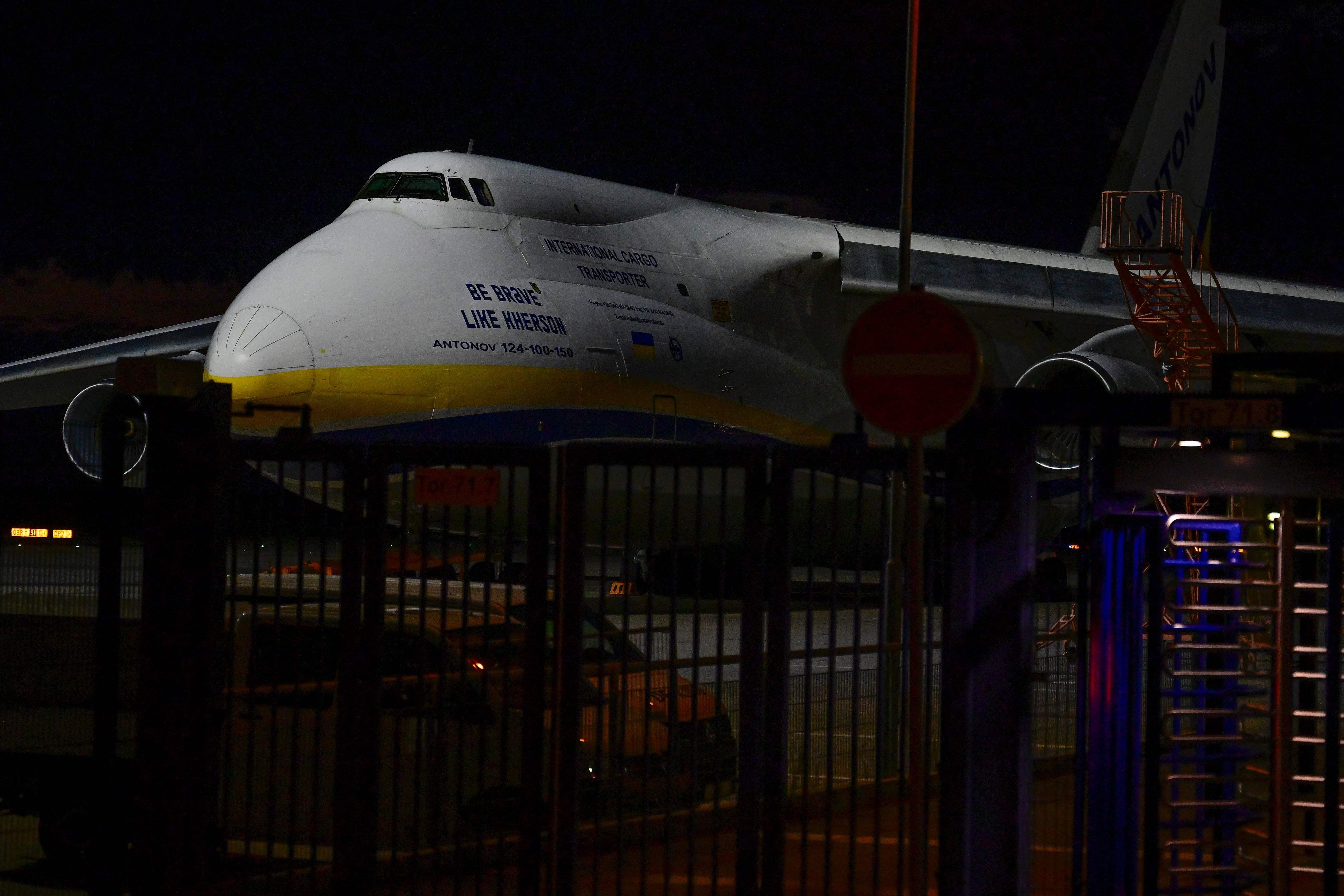 Ukrainisches Antonov-Frachtflugzeug steht nachts am Flughafen Leipzig-Halle hinter einem Zaun.