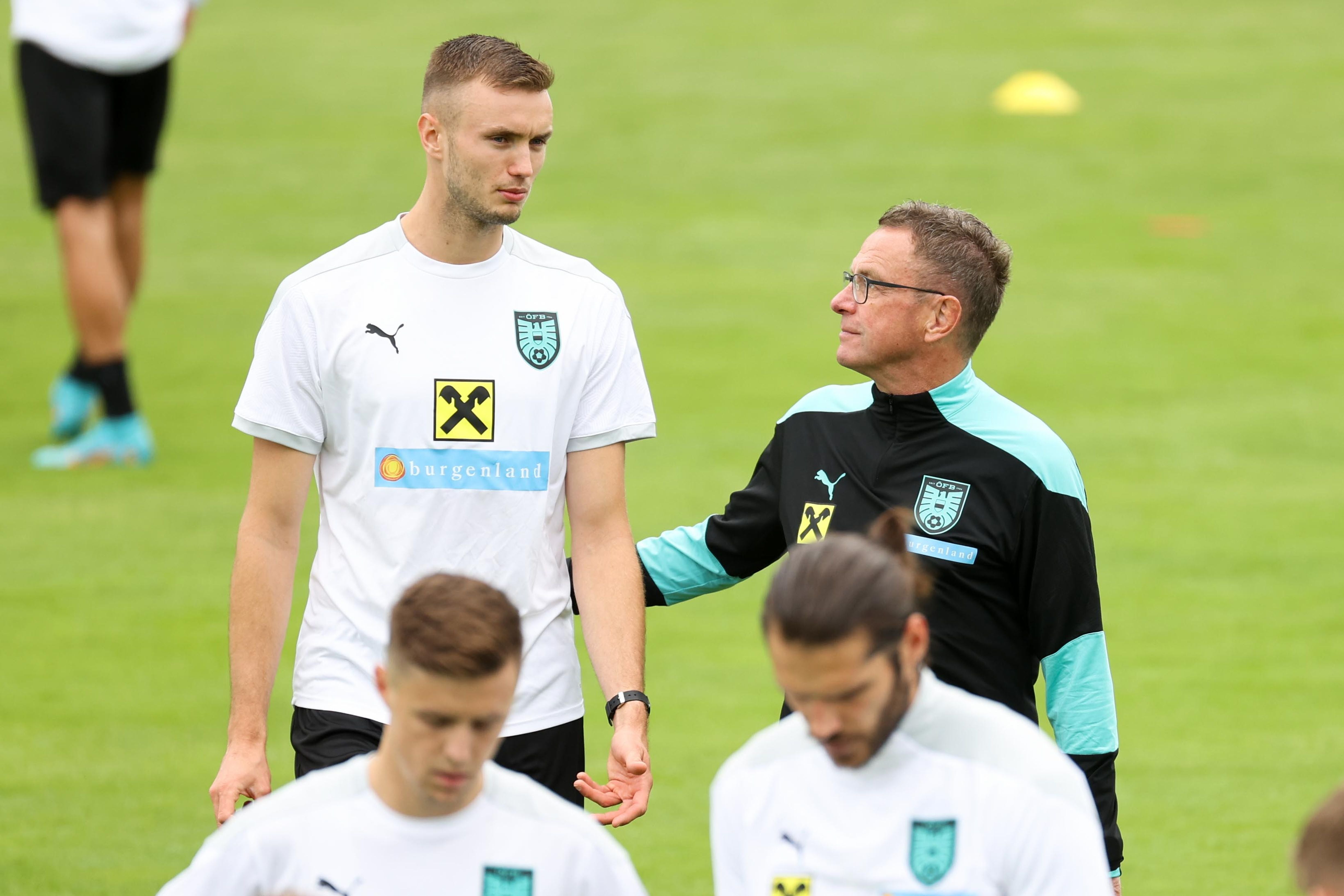 Trainer Ralf Rangnick spricht beim Training mit Sasa Kalajdzic auf einem Fußballfeld.