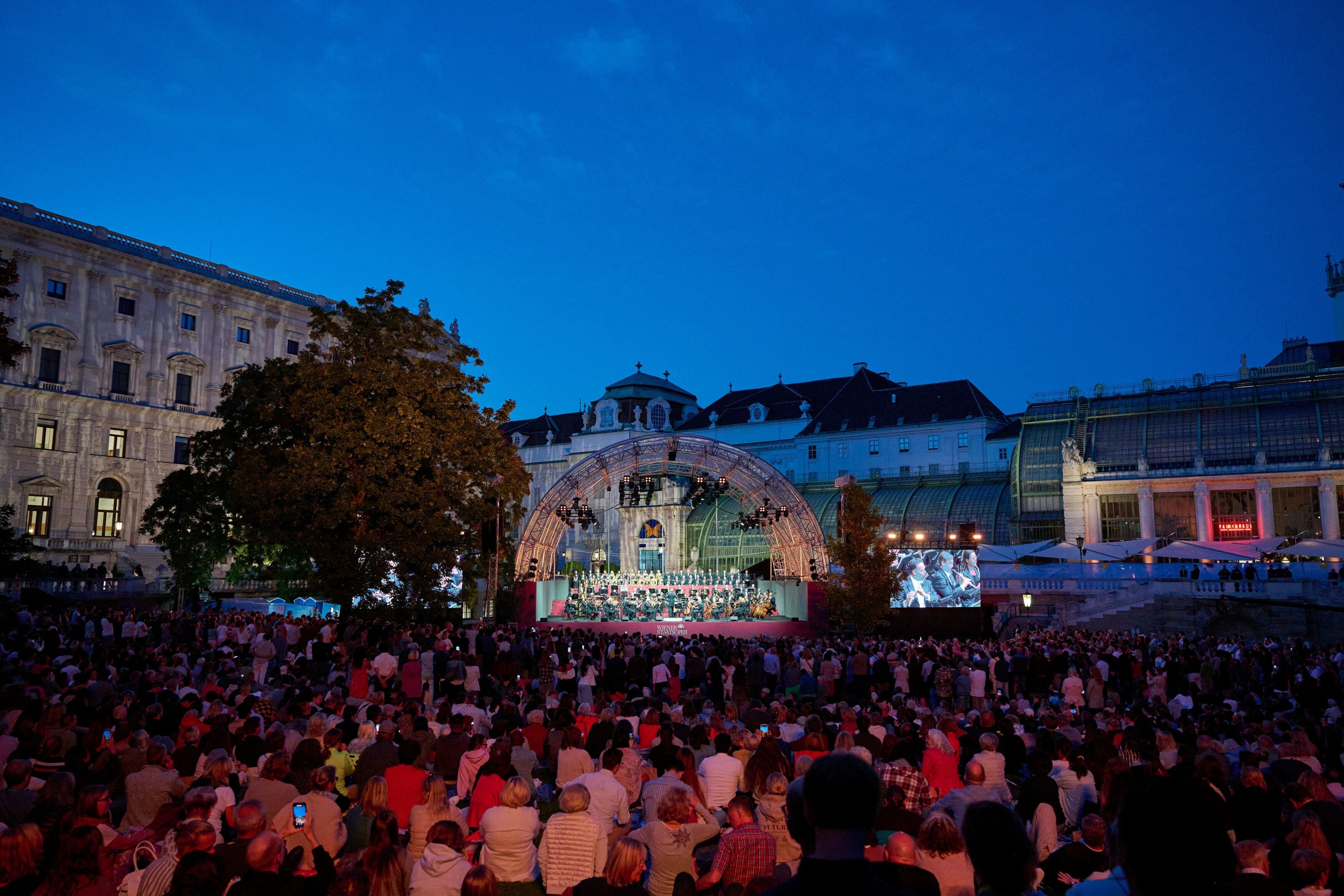 Großes Open-Air-Konzert im Wiener Burggarten mit vielen Zuschauern bei abendlicher Stimmung.
