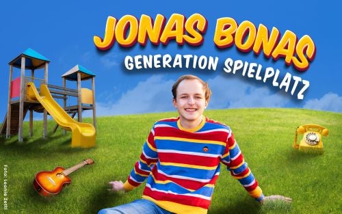 Junger Mann im bunten Pullover sitzt auf einer Wiese vor einem Spielplatz, Gitarre und Telefon daneben.