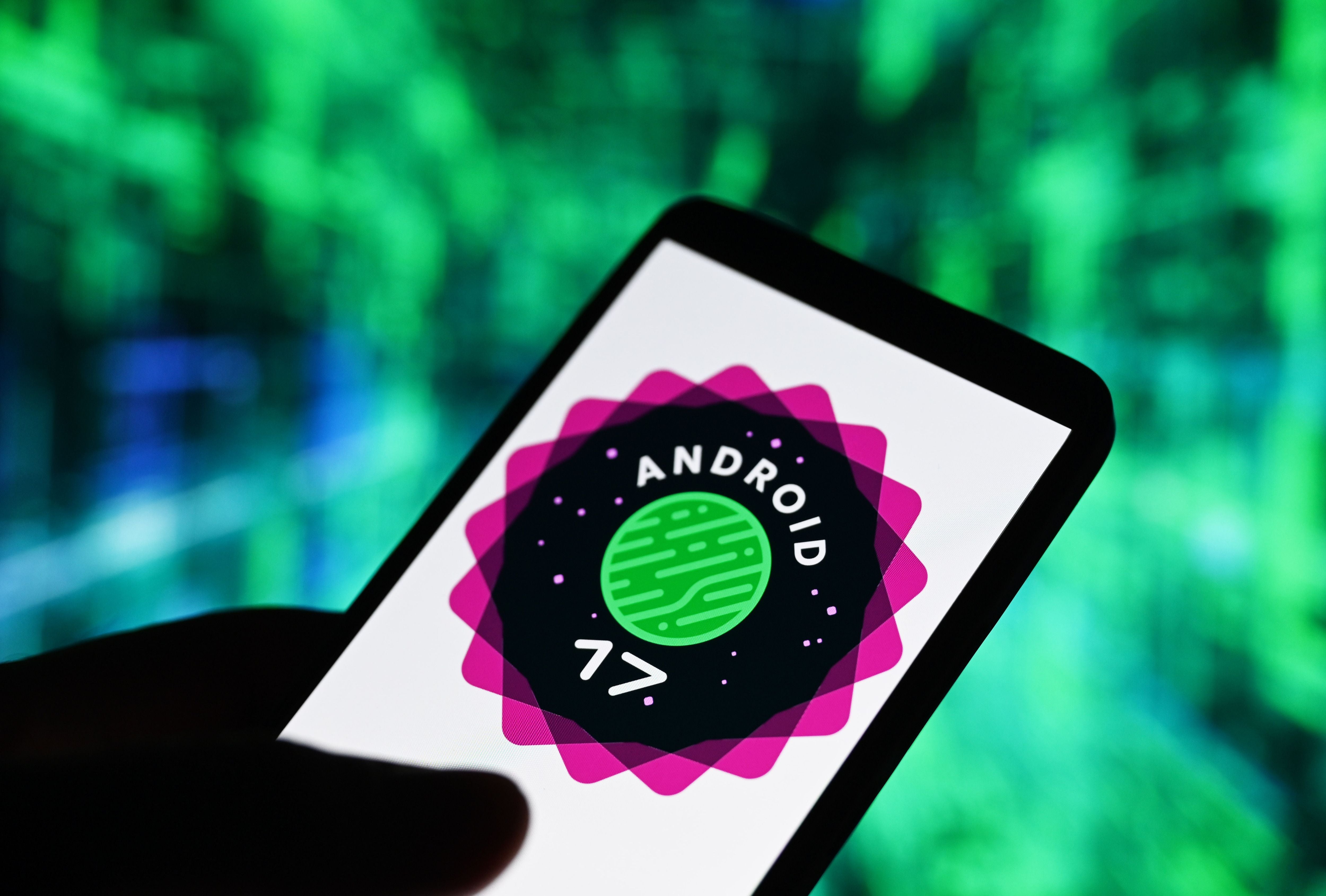 Smartphone mit Android-17-Logo vor unscharf grün-blauem Hintergrund.