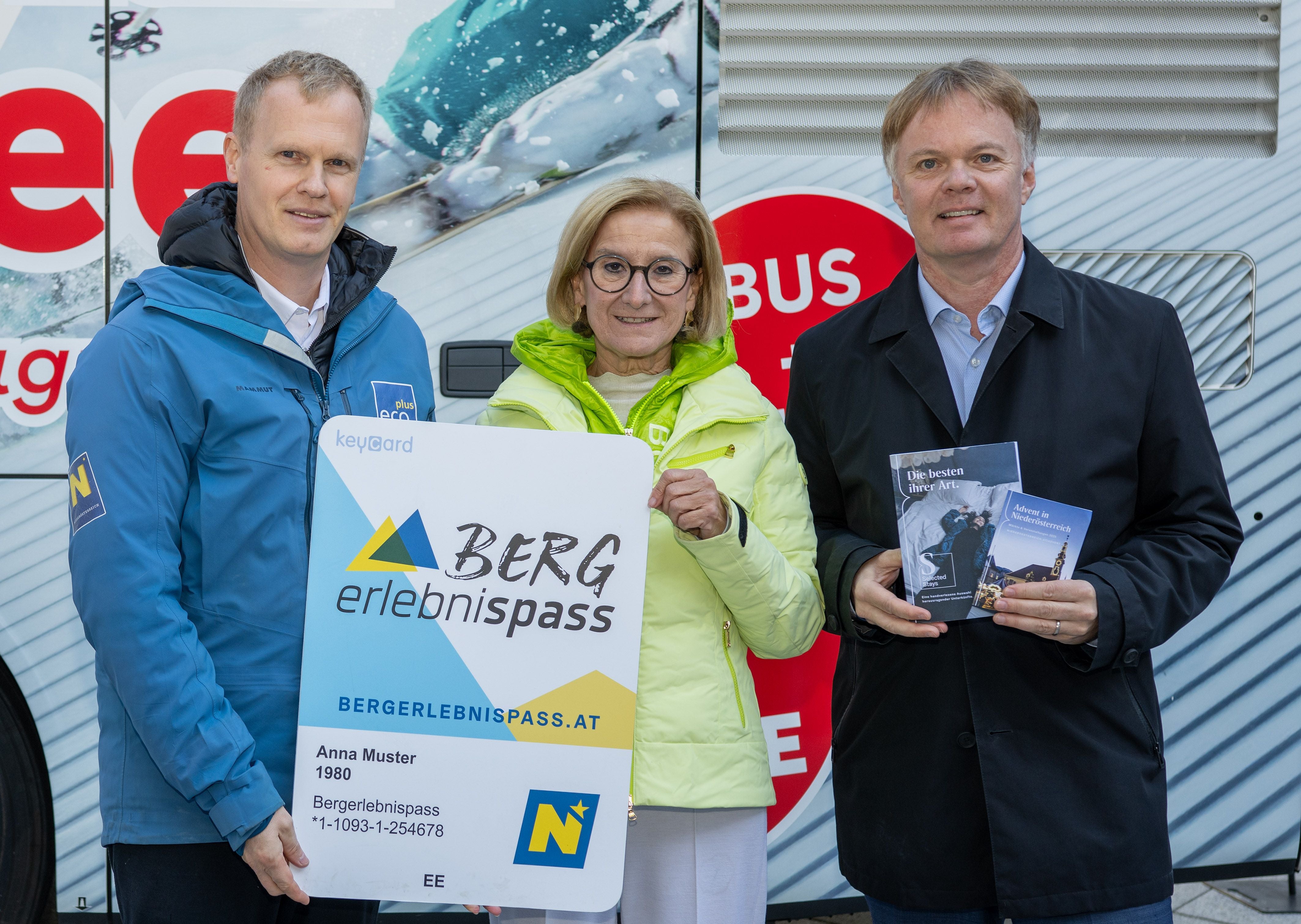 Drei Personen halten einen großen Berg-Erlebnispass und Werbebroschüren in der Hand.
