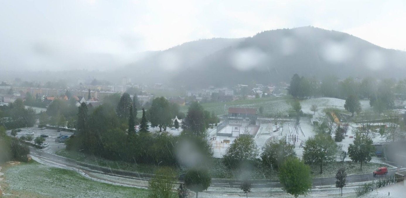 Blick auf Köflach mit Bäumen und Straßen, die von Hagel bedeckt sind.