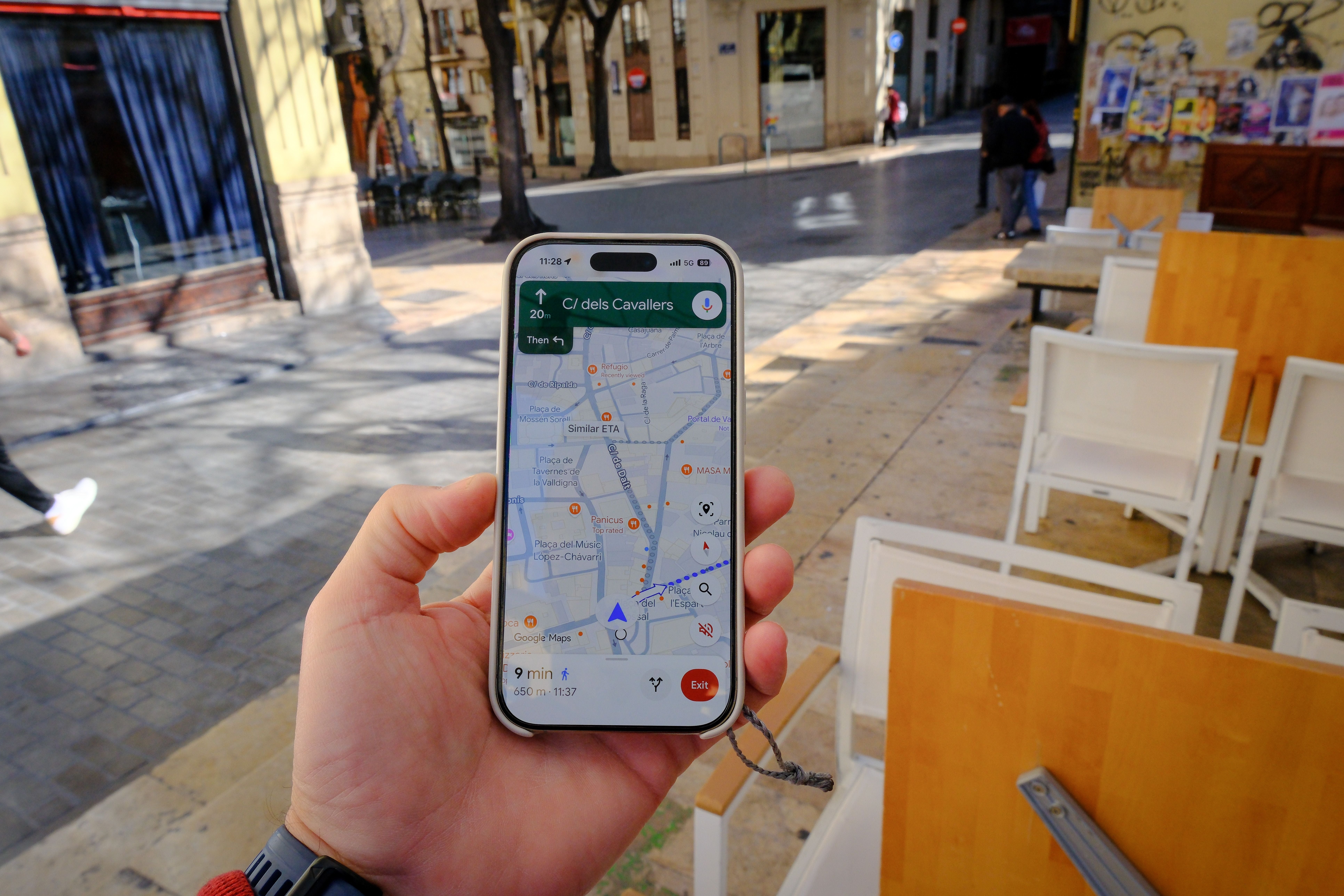 Eine Person hält ein Smartphone mit geöffneter Google Maps Navigation in einer Stadt.