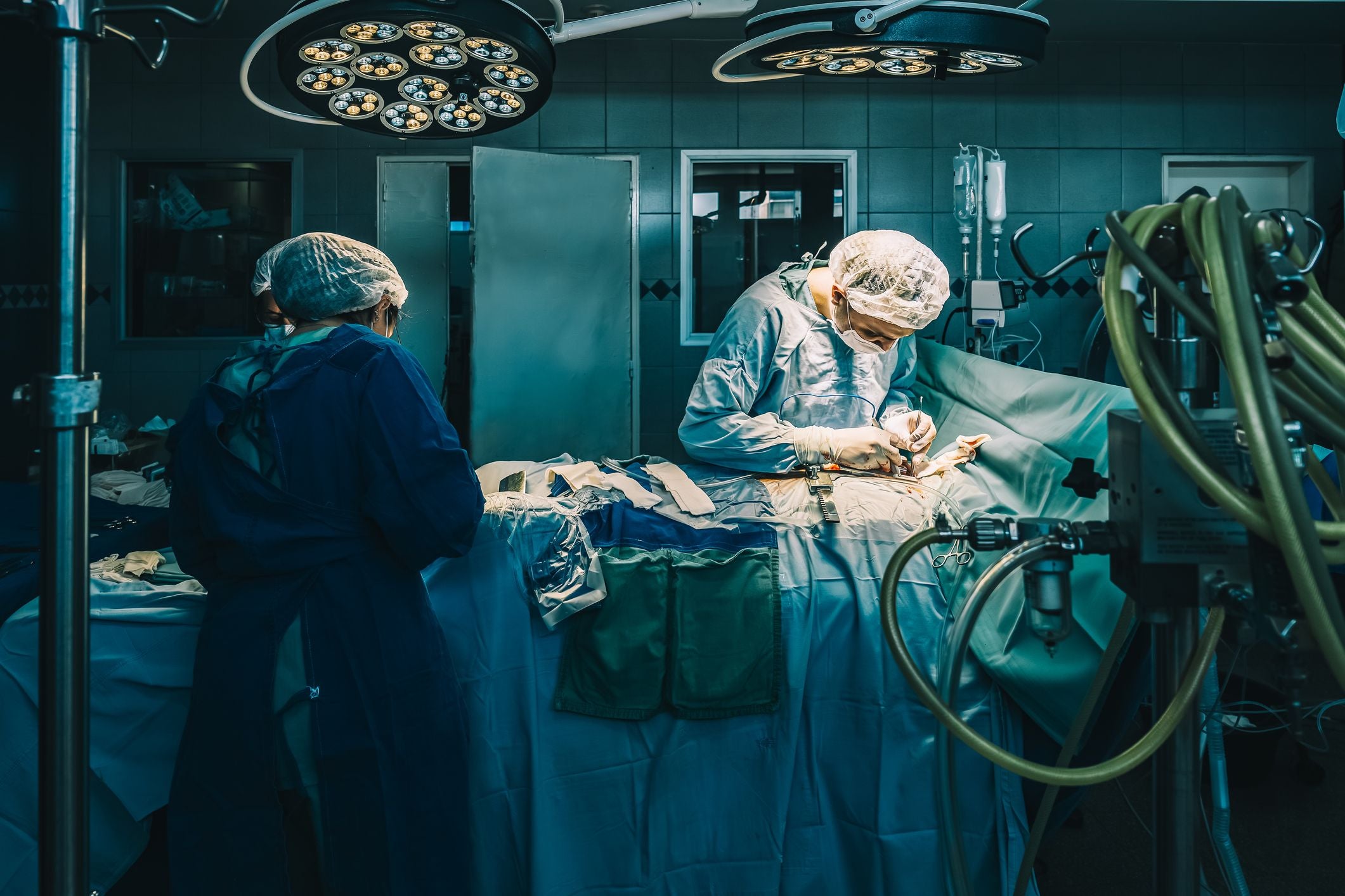 Zwei Chirurgen führen eine Operation in einem hell beleuchteten Operationssaal durch.