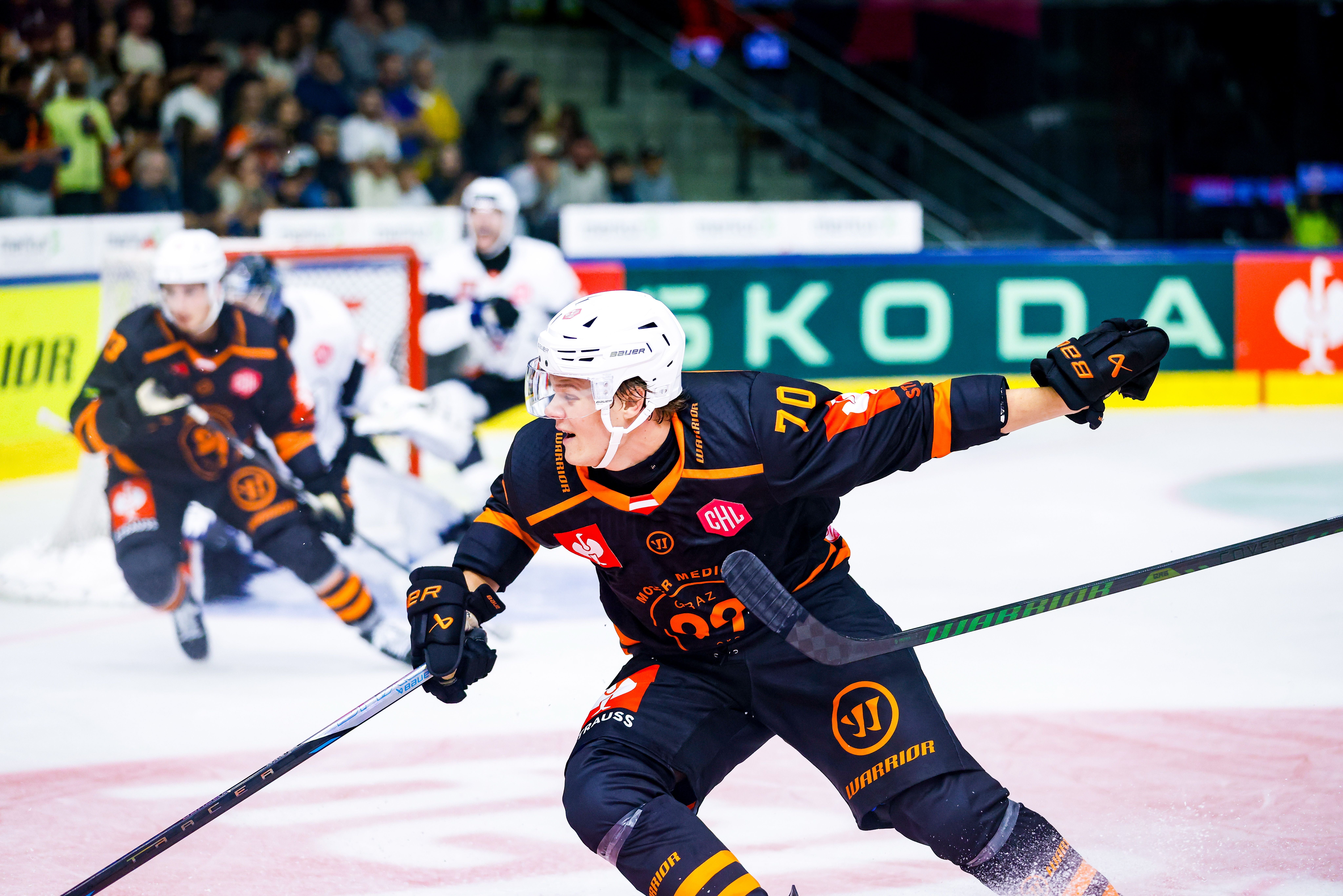 Eishockeyspieler im schwarzen Trikot beim Spiel vor dem Tor auf dem Eis.