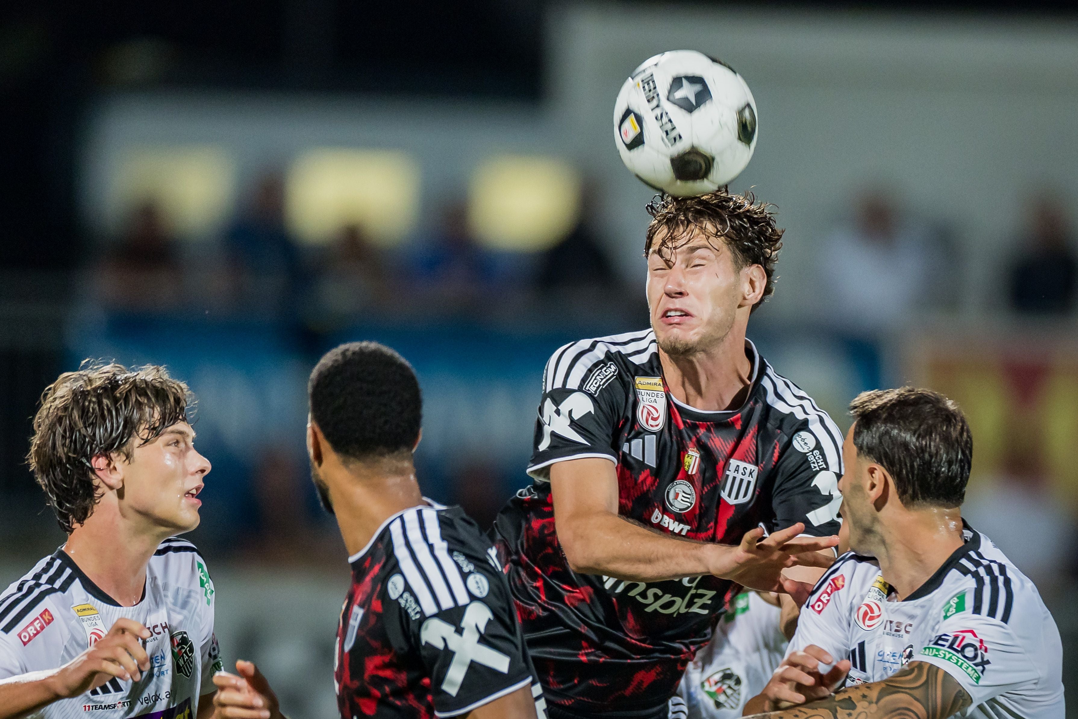 Mehrere Fußballspieler kämpfen bei einem Kopfballduell um den Ball.