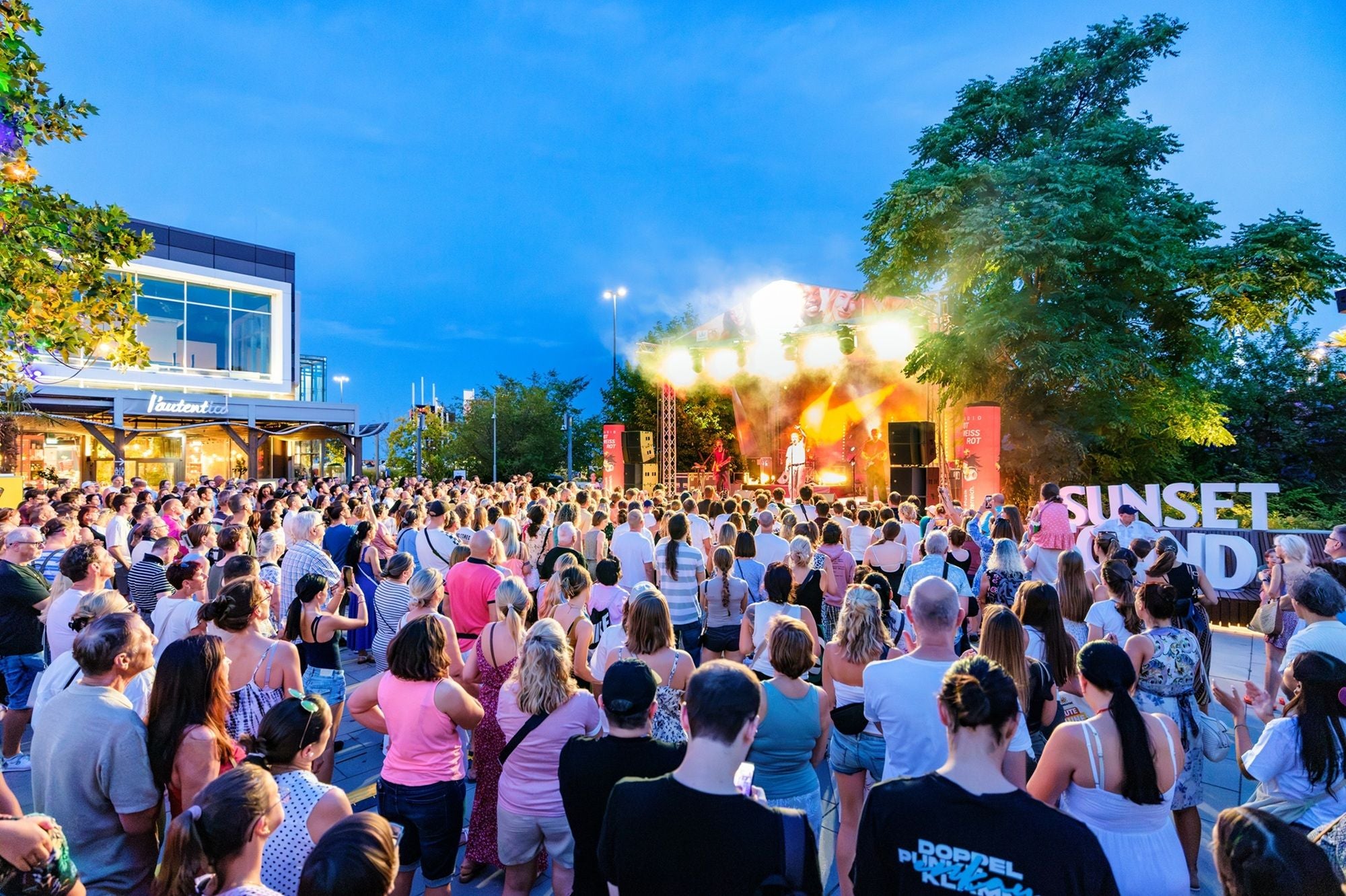 Große Menschenmenge bei einem Open-Air-Konzert auf den Multiplex Terrassen bei Sonnenuntergang.
