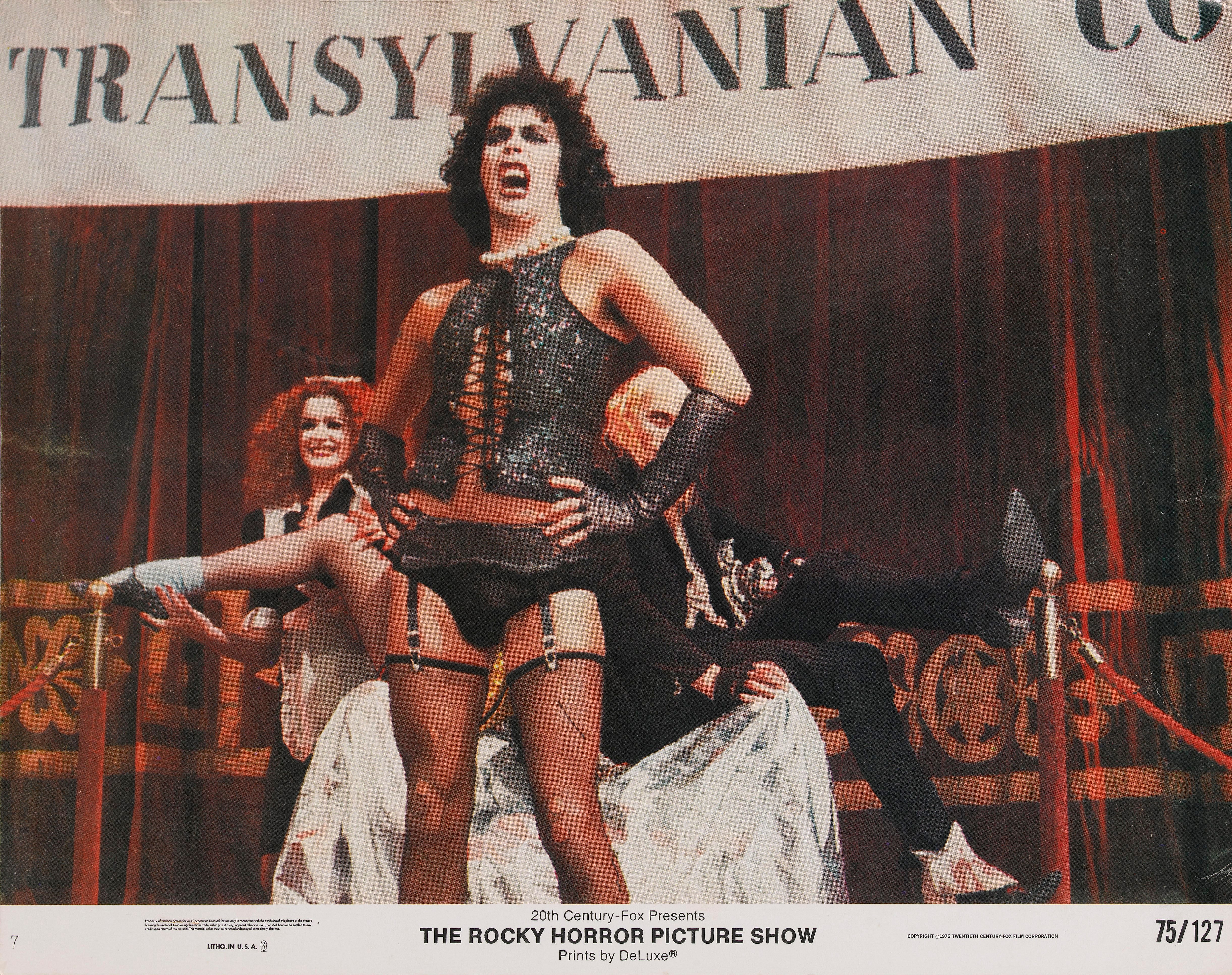 Drei Figuren in extravaganten Kostümen auf einer Bühne bei "The Rocky Horror Picture Show".