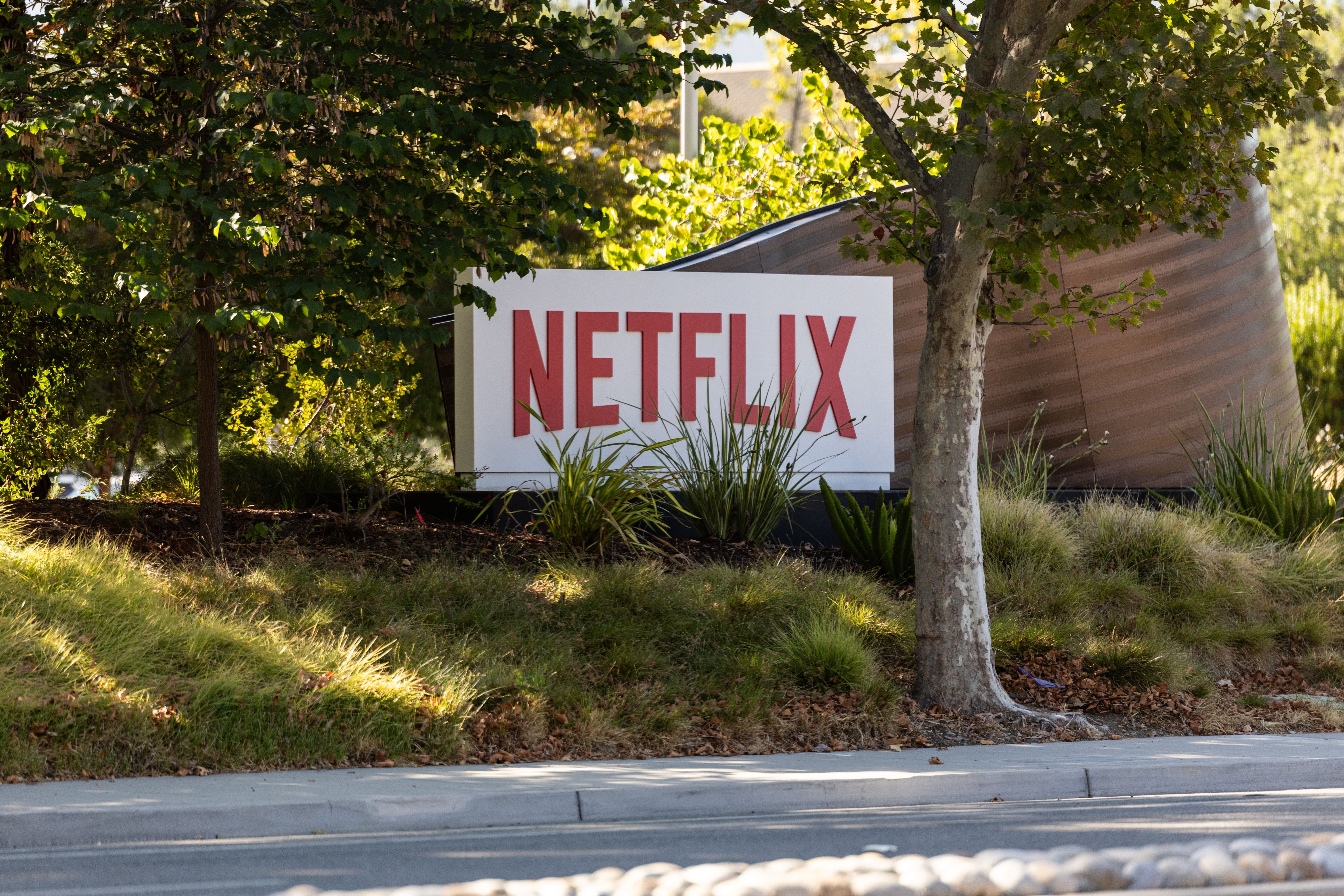 Netflix-Firmenschild steht draußen zwischen Bäumen und Sträuchern in Los Gatos, Kalifornien.