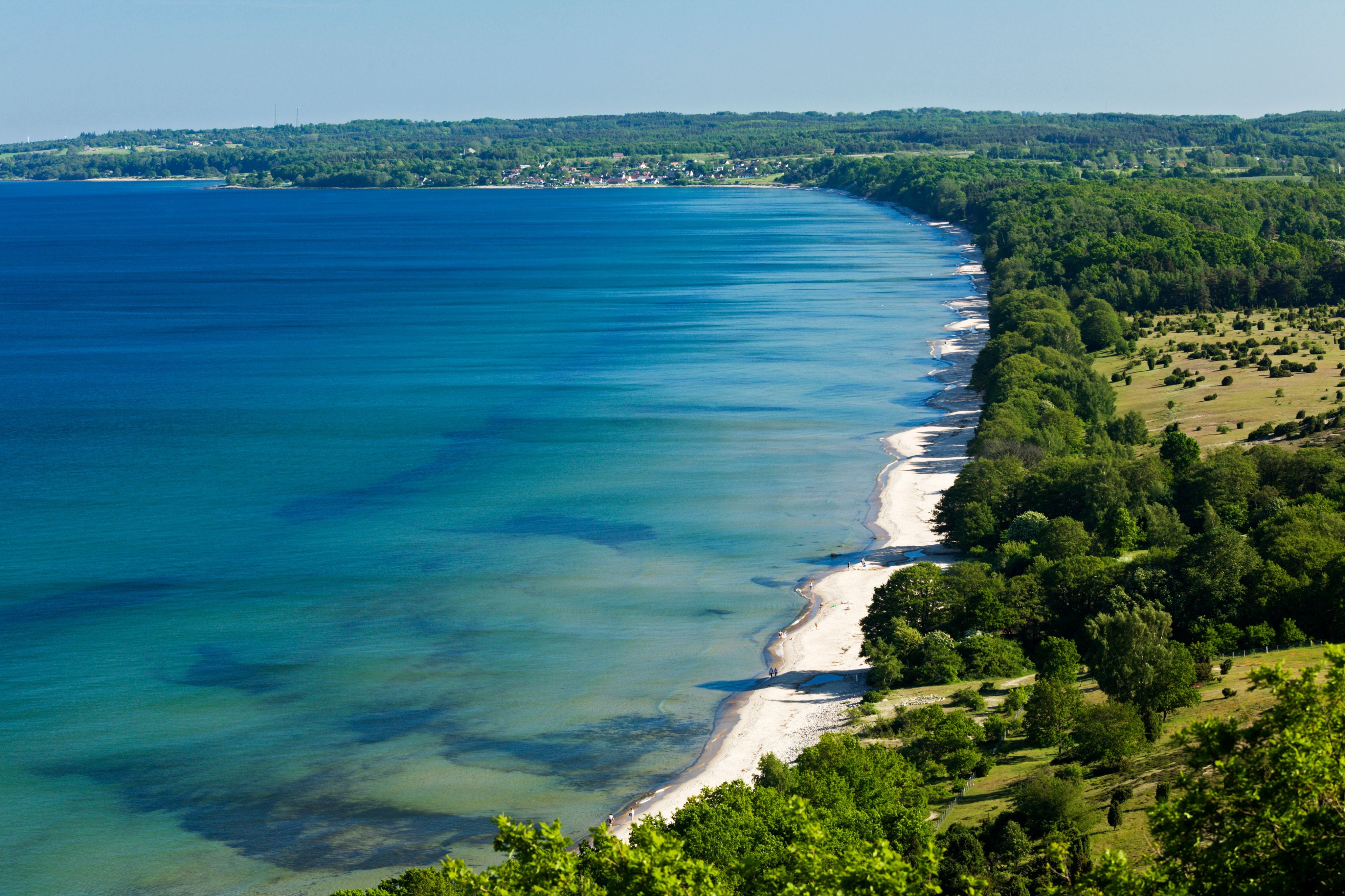 Küste mit weißem Sandstrand, klarem blauen Meer und grünem Wald im Stenshuvud Nationalpark, Schweden.