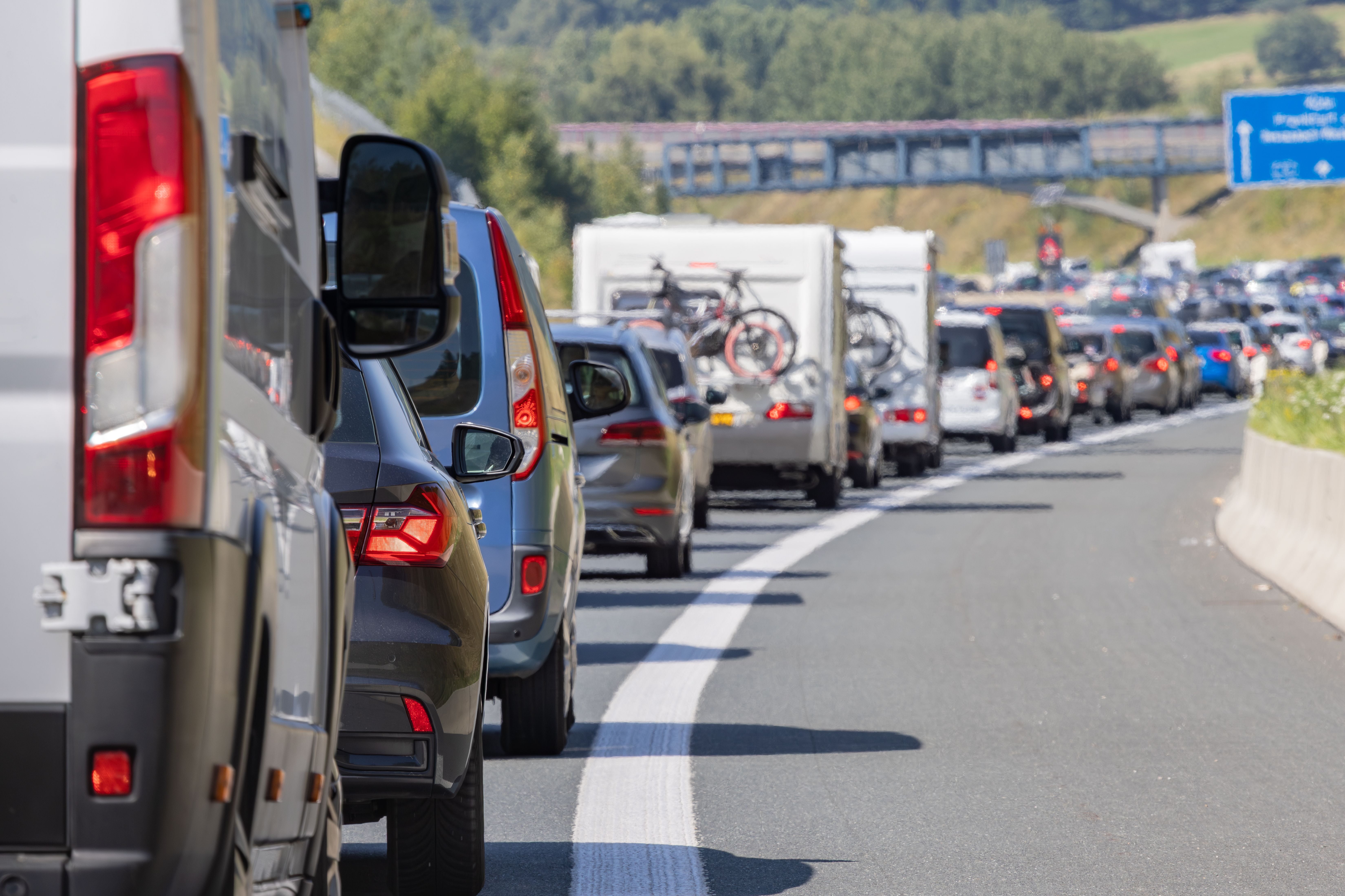 Stau mit vielen Autos und Wohnmobilen auf einer deutschen Autobahn bei sonnigem Wetter.