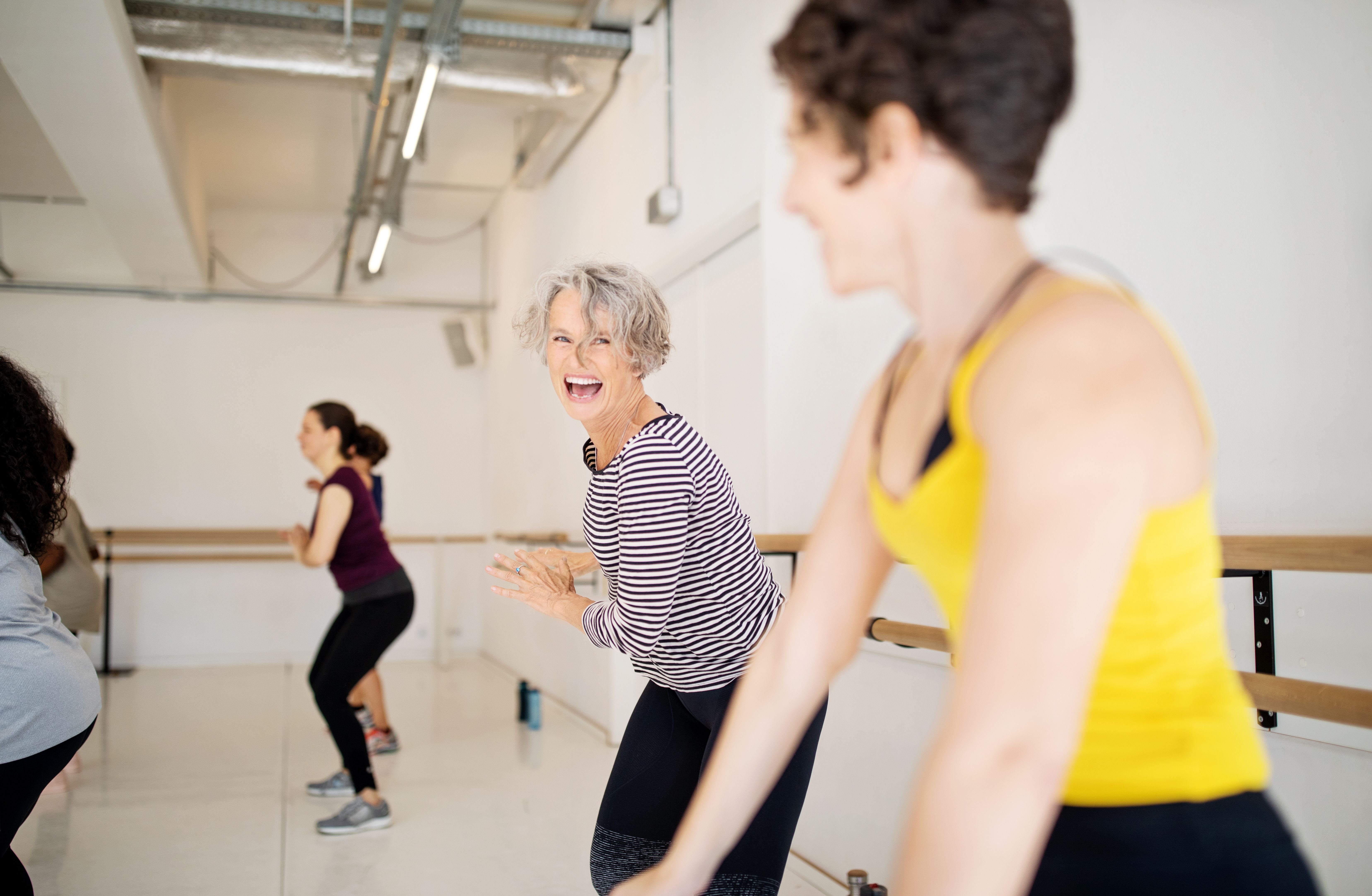 Frauen tanzen fröhlich zusammen in einem Fitnessstudio.