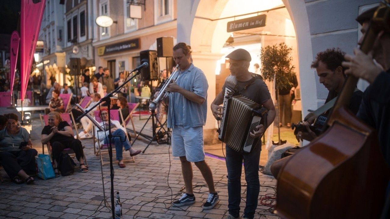 Straßenmusiker spielen bei der Waidhofner Einkaufsnacht, Zuschauer sitzen auf Liegestühlen.