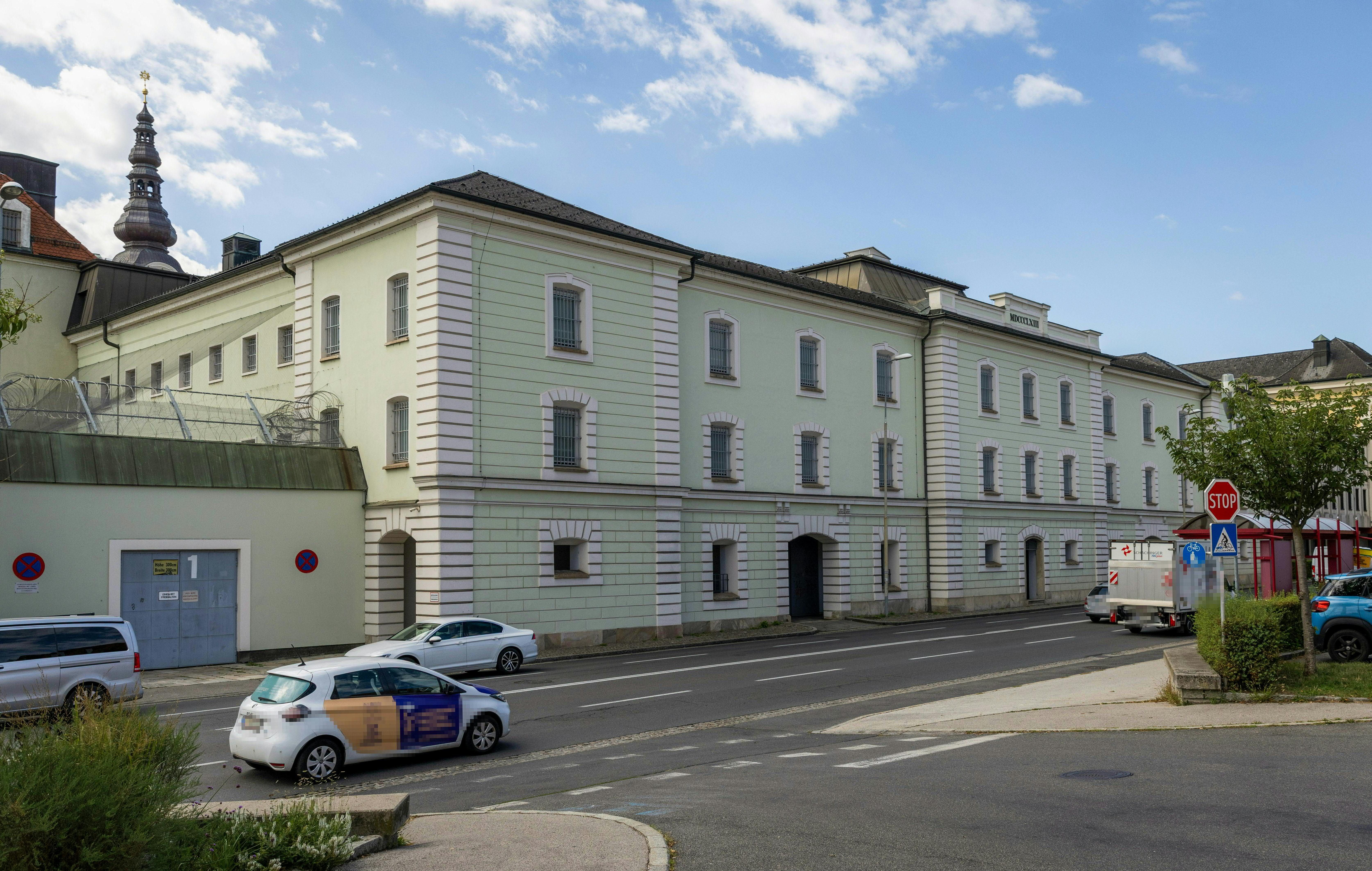Außenansicht der Justizanstalt Klagenfurt an einer Straße unter blauem Himmel.