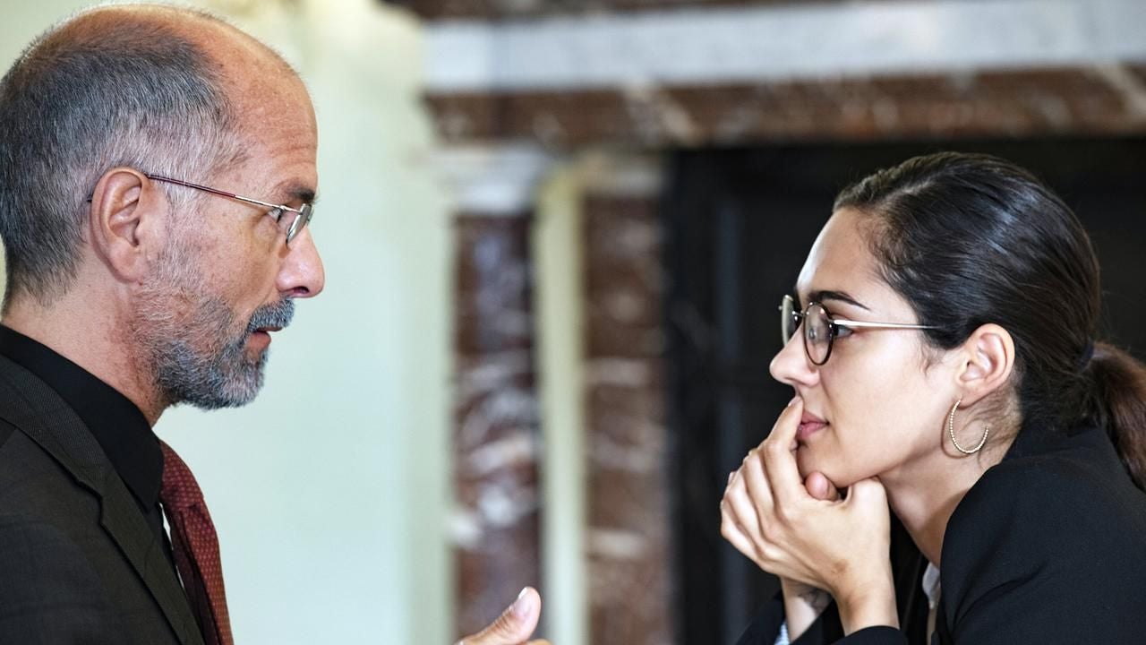 Ein Mann und eine Frau im Anzug führen ein intensives Gespräch miteinander.