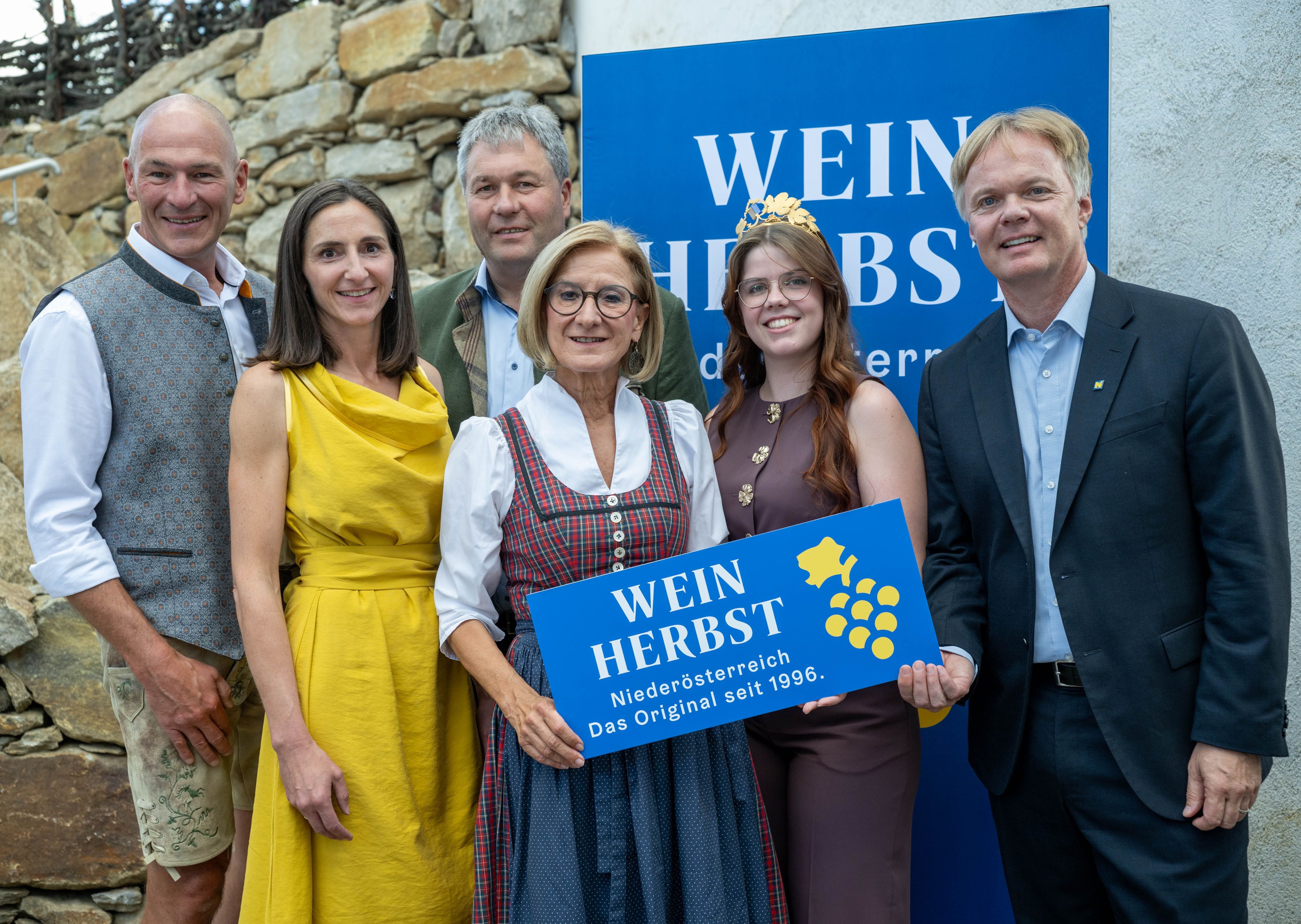 Sechs Personen posieren bei der Eröffnung des 31. Weinherbsts Niederösterreich mit Schild.