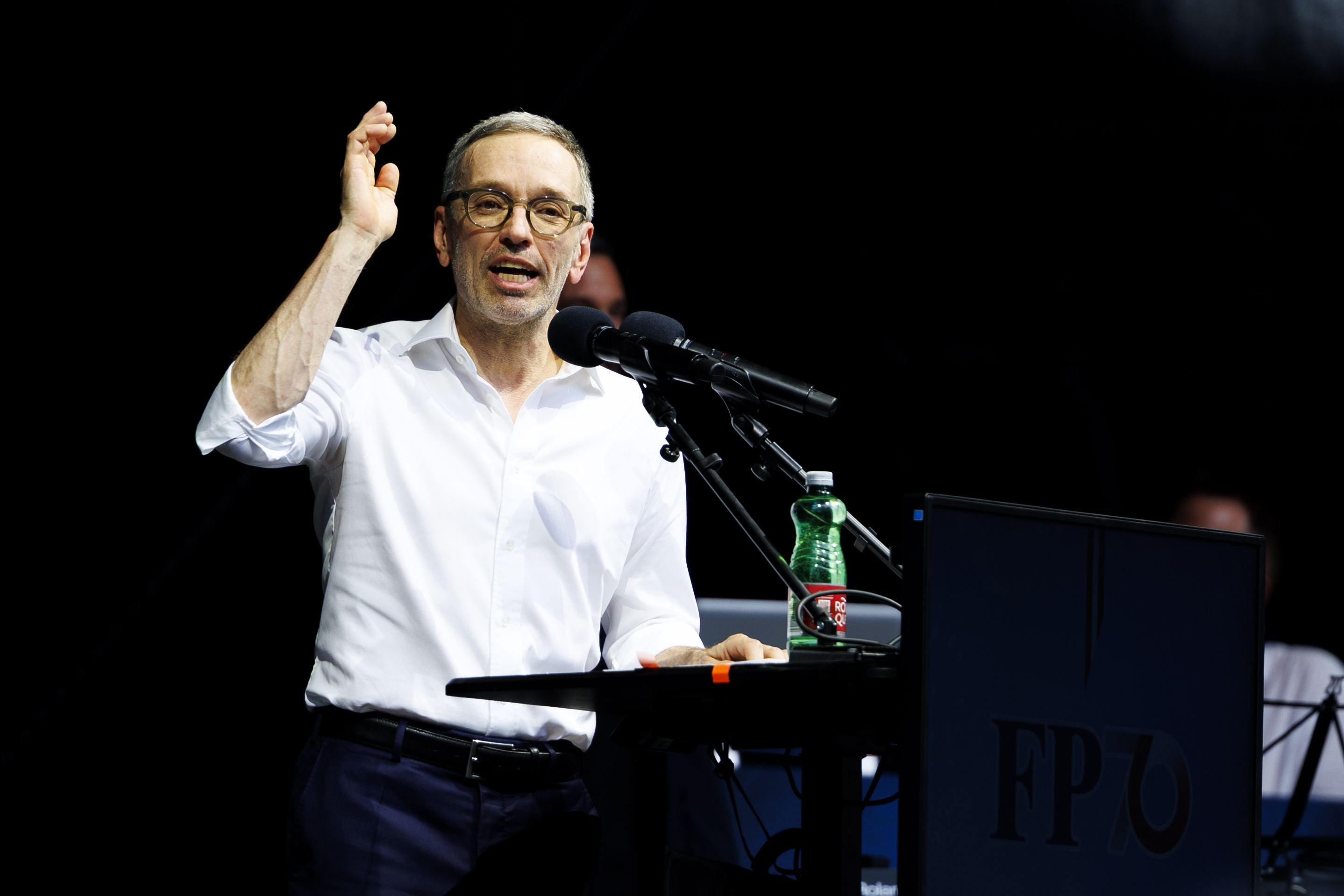 Ein Mann hält eine Rede an einem Mikrofon bei einer Veranstaltung der FPÖ in Wien.