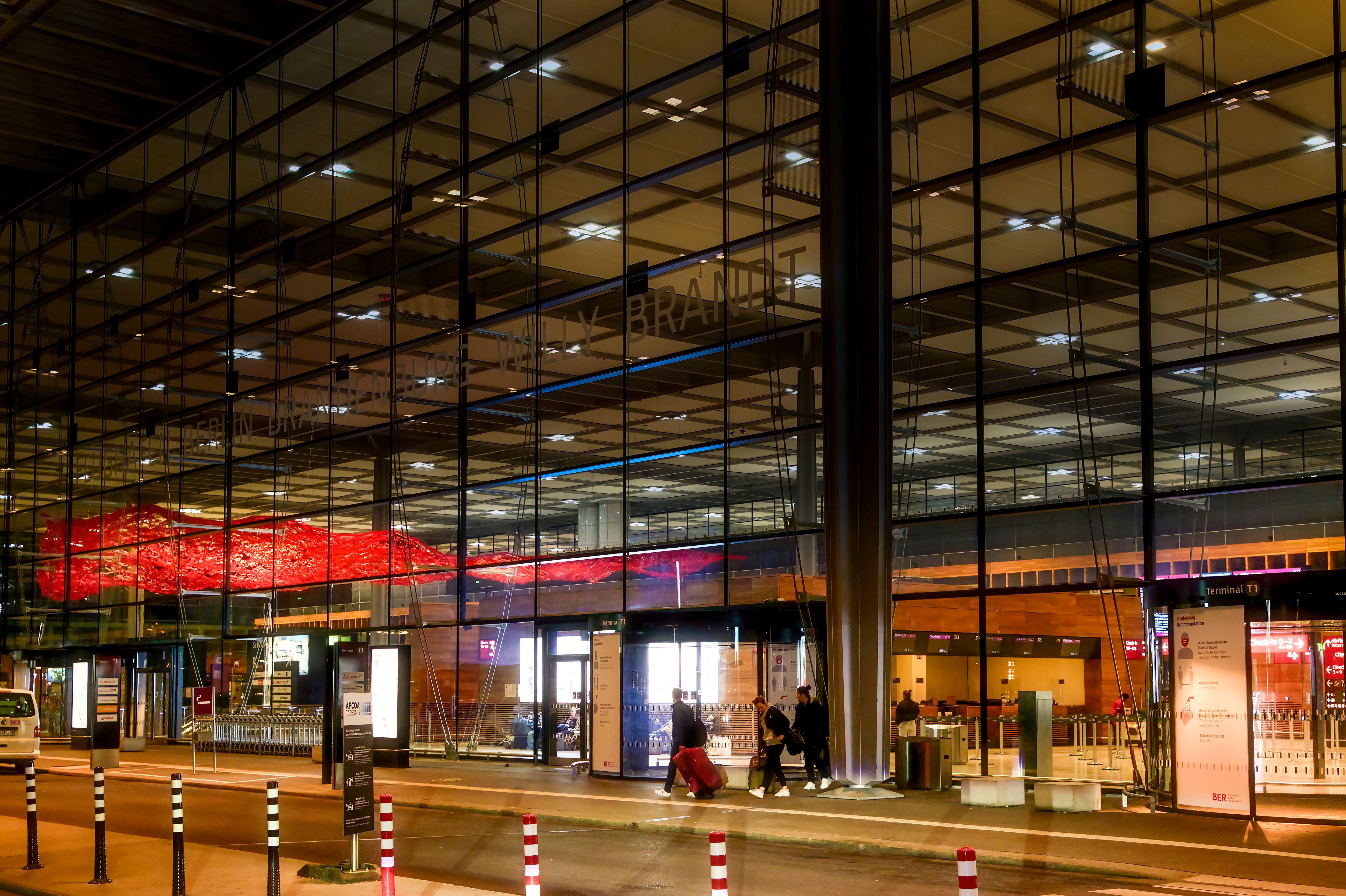 Empfangsgebäude des BER Flughafens bei Nacht mit reduzierter Fassadenbeleuchtung.