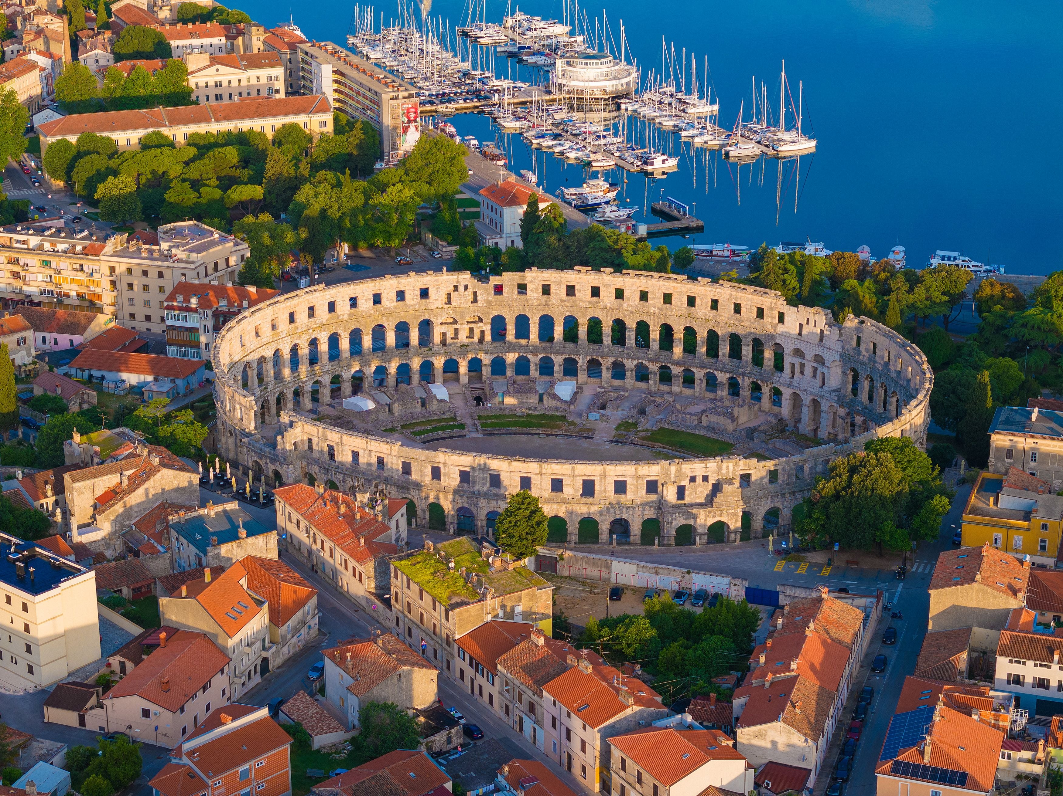 Luftaufnahme des römischen Amphitheaters von Pula mit Hafen und umliegender Stadt.
