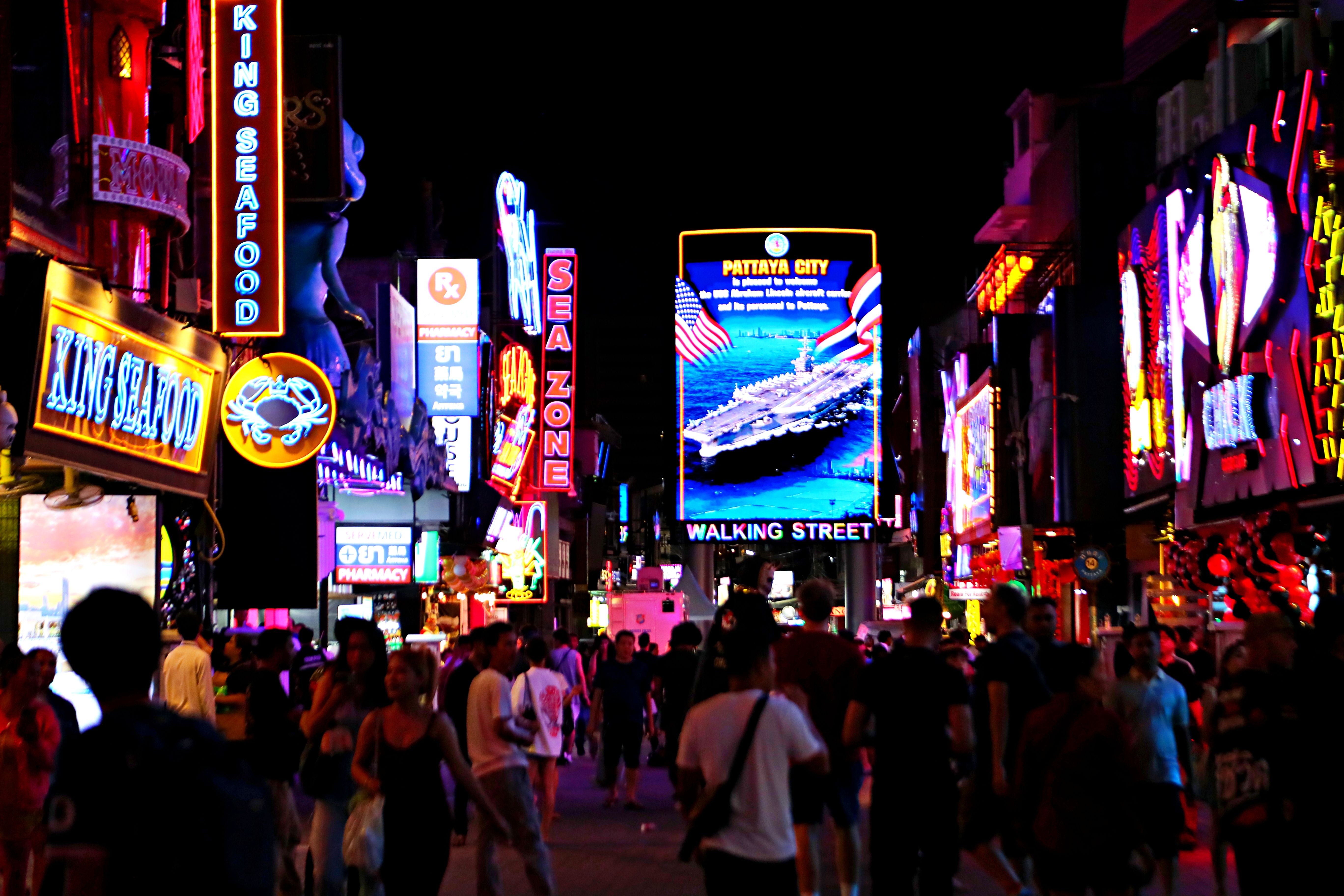 Menschen gehen nachts über die bunte, neonbeleuchtete Walking Street in Pattaya, Thailand.