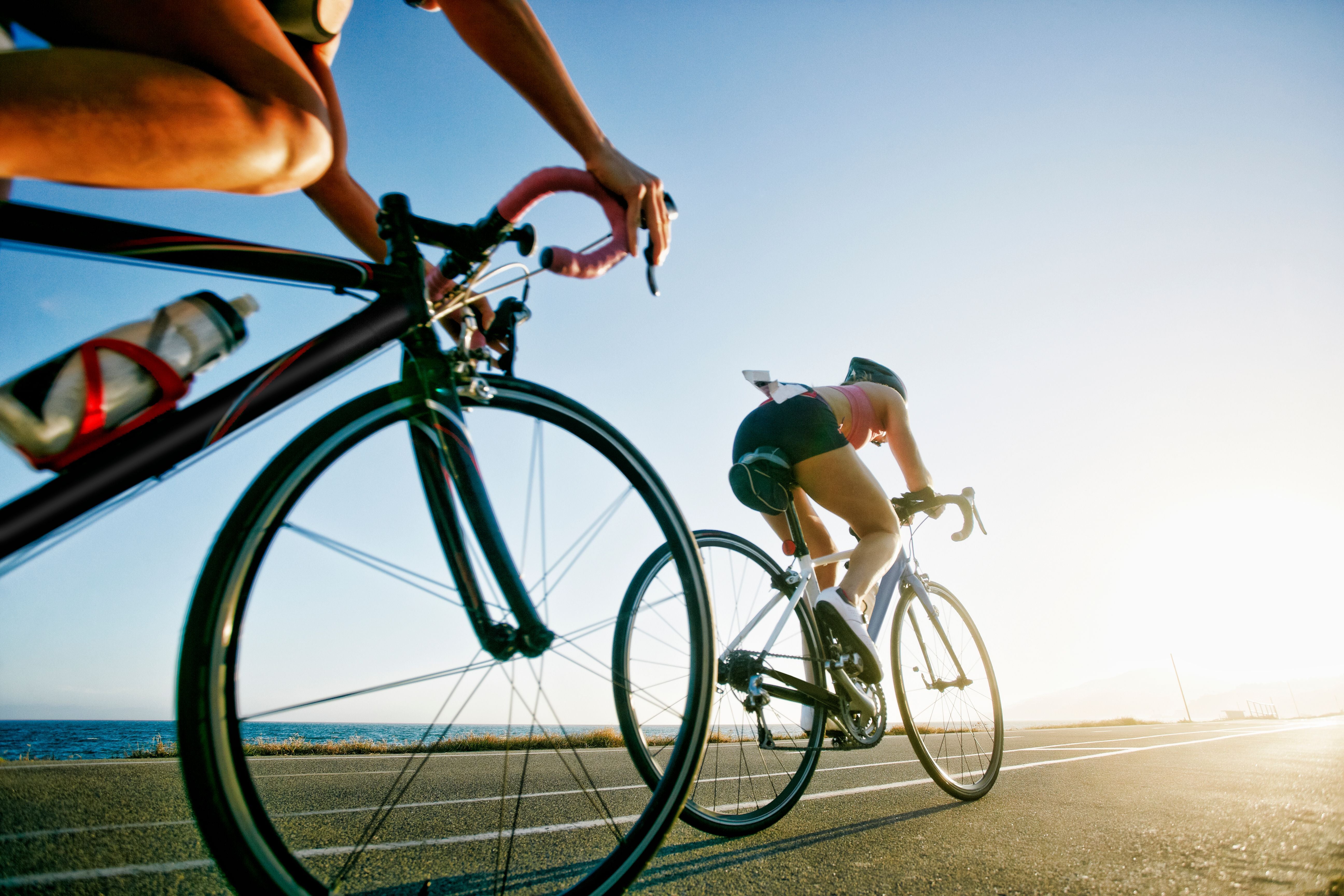 Zwei Radfahrerinnen fahren bei Sonnenaufgang am Meer während eines Triathlons.