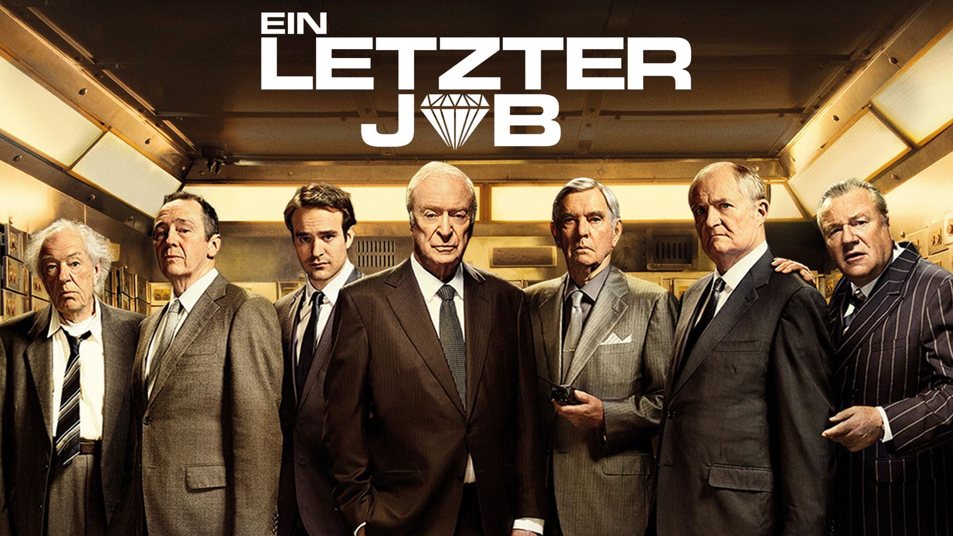 Sieben ältere Männer in Anzügen stehen nebeneinander in einem Tresorraum, darüber der Schriftzug „Ein letzter Job“.