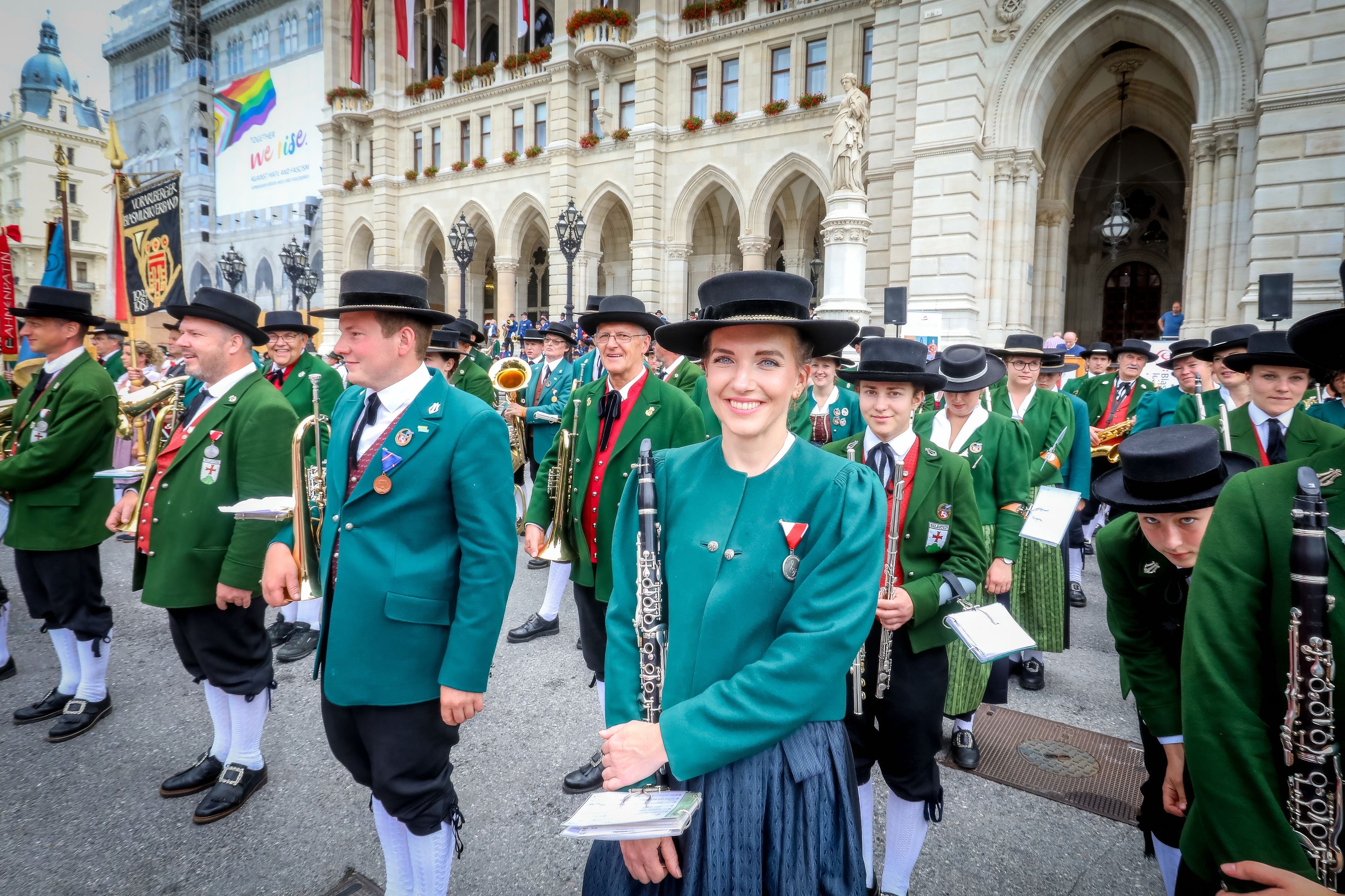 Blasmusikanten in traditionellen Trachten versammeln sich vor dem Wiener Rathaus zur Parade.