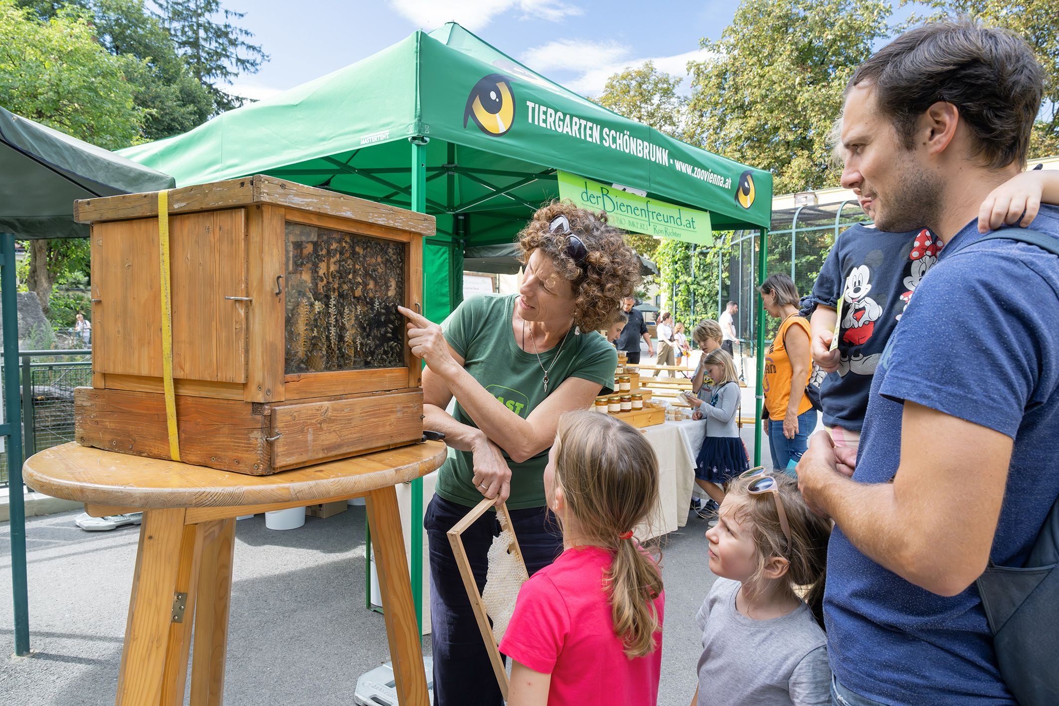 Eine Frau erklärt Kindern und Erwachsenen einen Bienenstock bei Artenschutztagen im Tiergarten Schönbrunn.