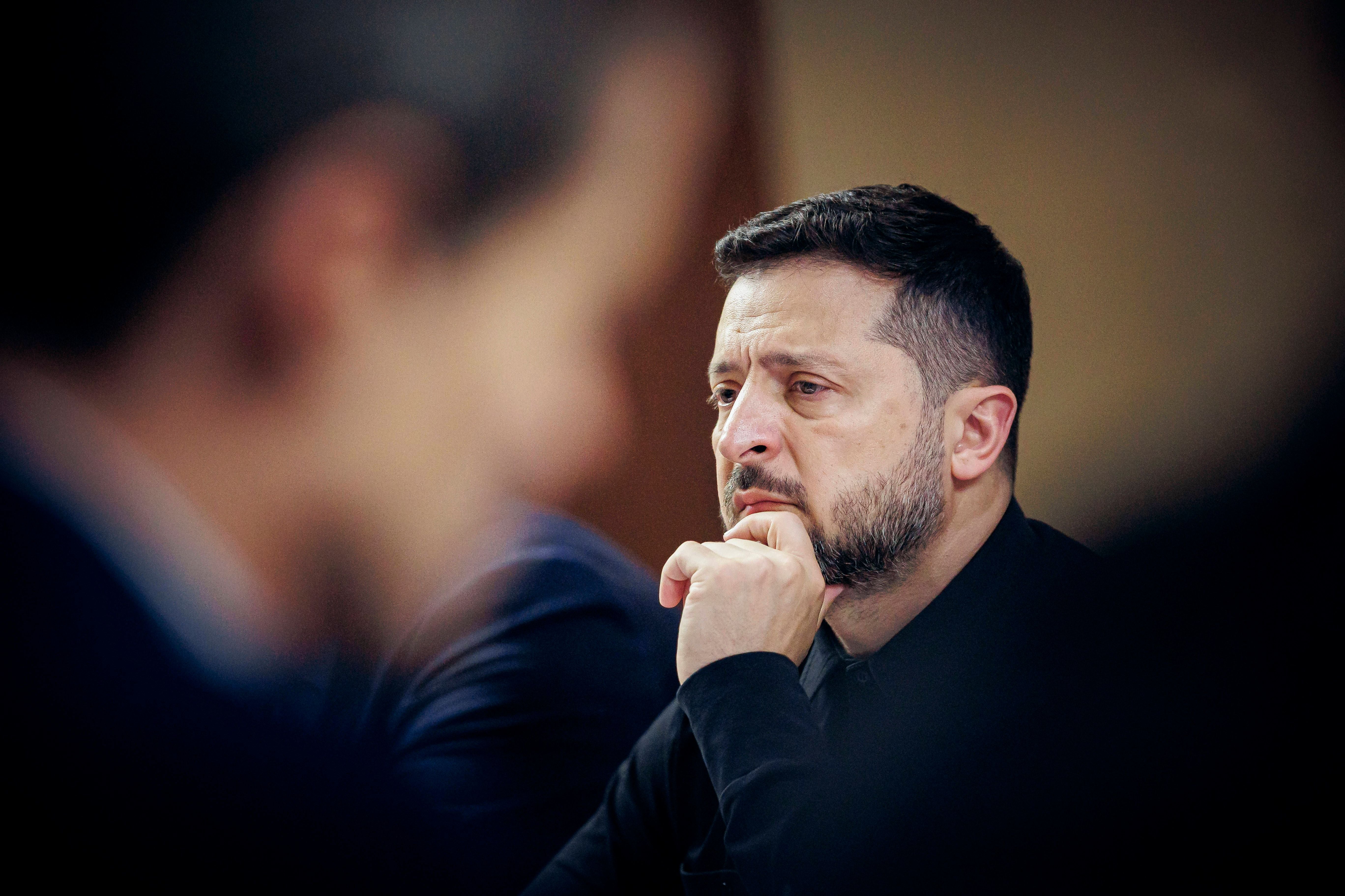 Ein Mann sitzt nachdenklich mit der Hand am Kinn in einem Konferenzraum.