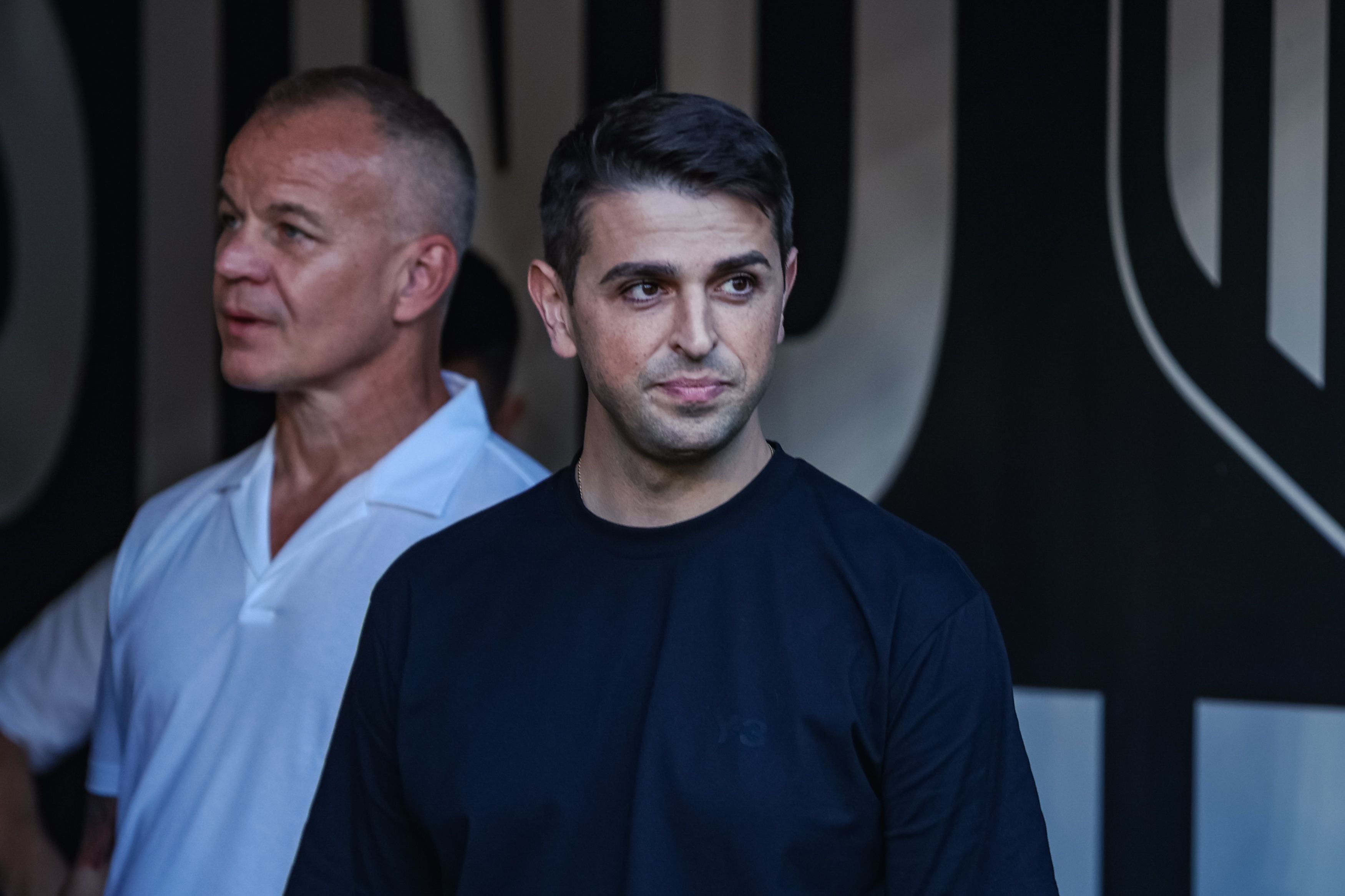 LASK-Sportchef Dino Buric steht im schwarzen Oberteil im Innenbereich des Stadions, während LASK-Präsident Siegmund Gruber im Hintergrund zu sehen ist.