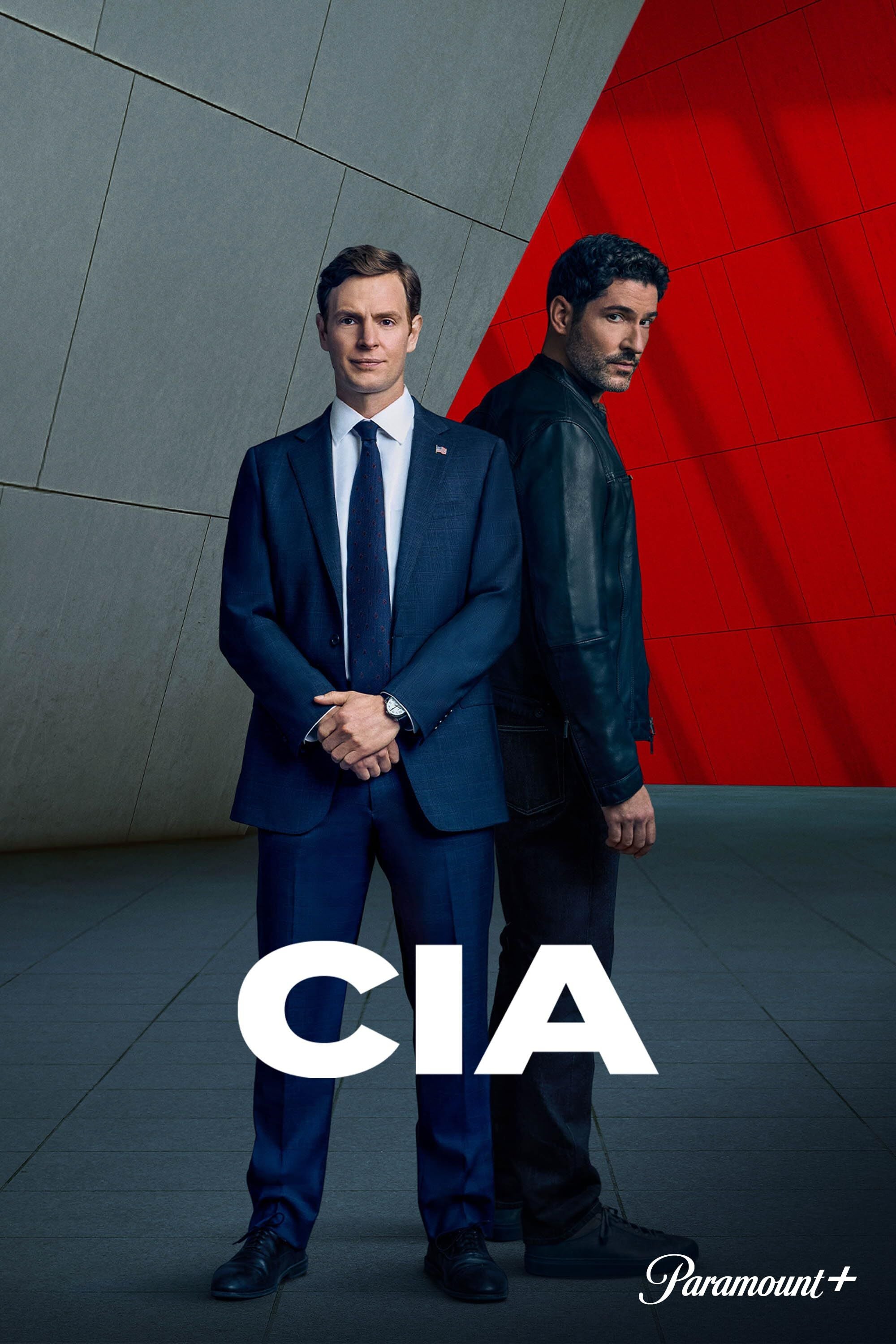 Zwei Männer stehen Rücken an Rücken vor einer grauen und roten Wand, mit der Aufschrift "CIA".