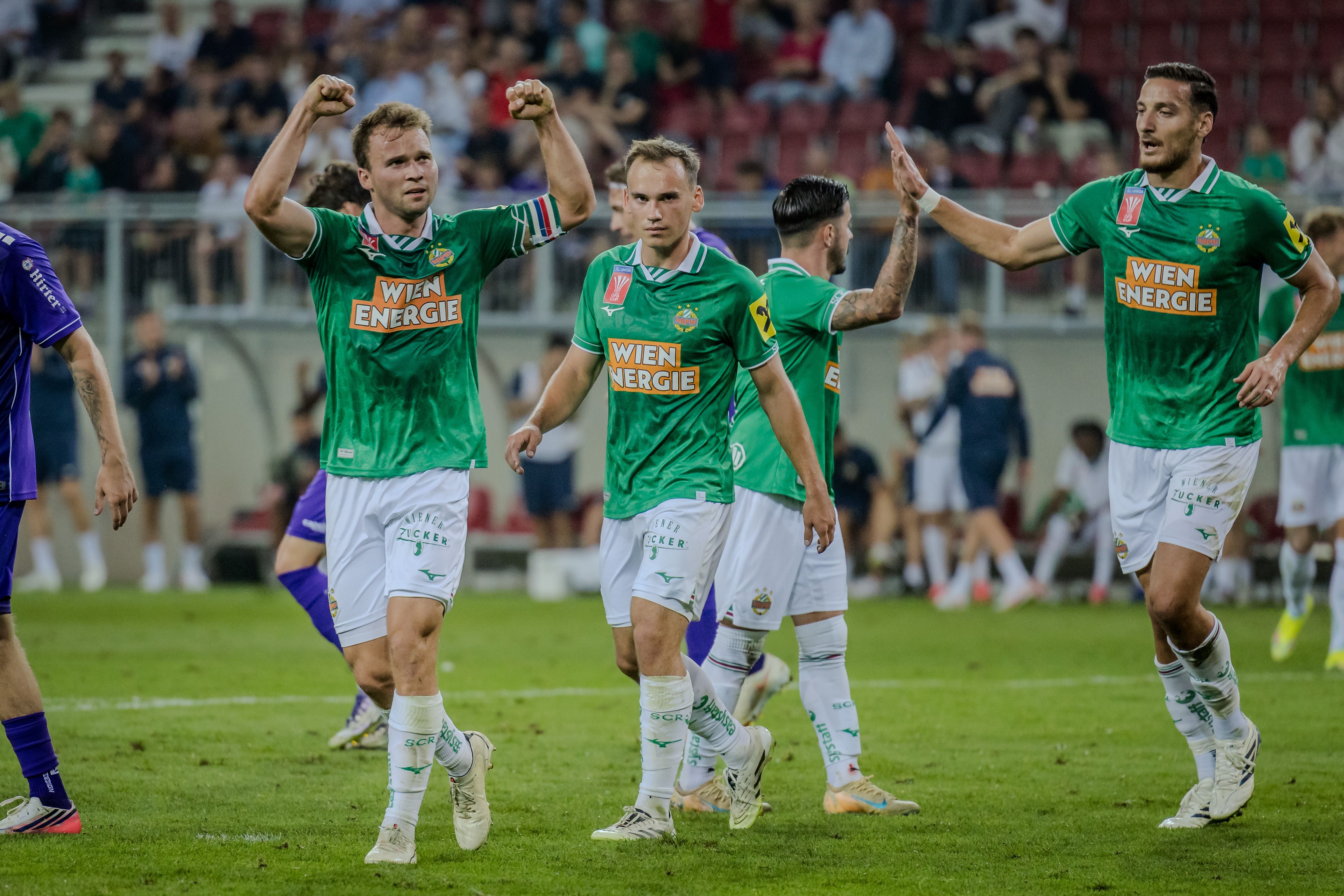 Fußballspieler von Rapid Wien jubeln nach einem Tor auf dem Spielfeld.