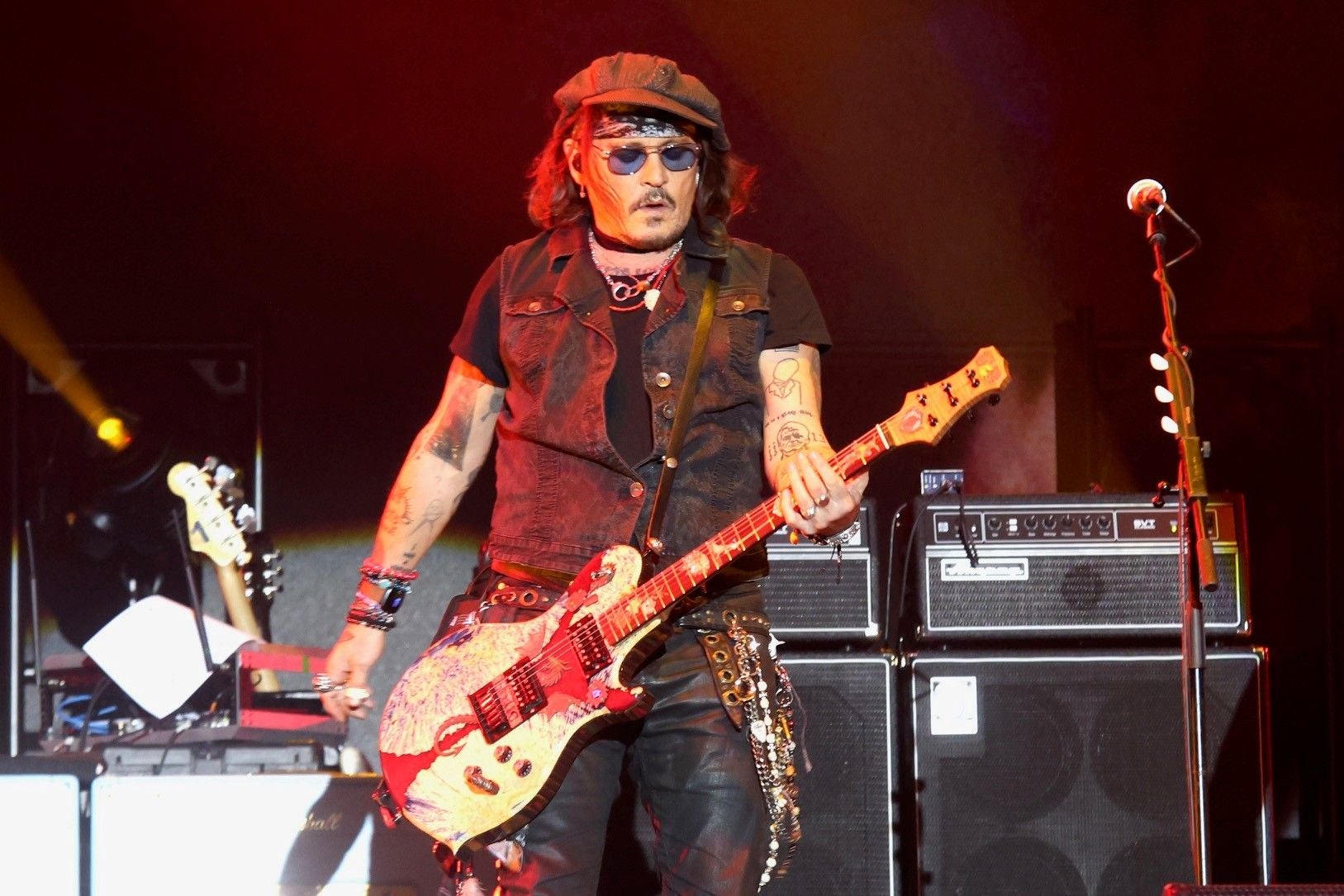 Ein Musiker der Hollywood Vampires spielt E-Gitarre auf einer Bühne mit Verstärkern im Hintergrund.