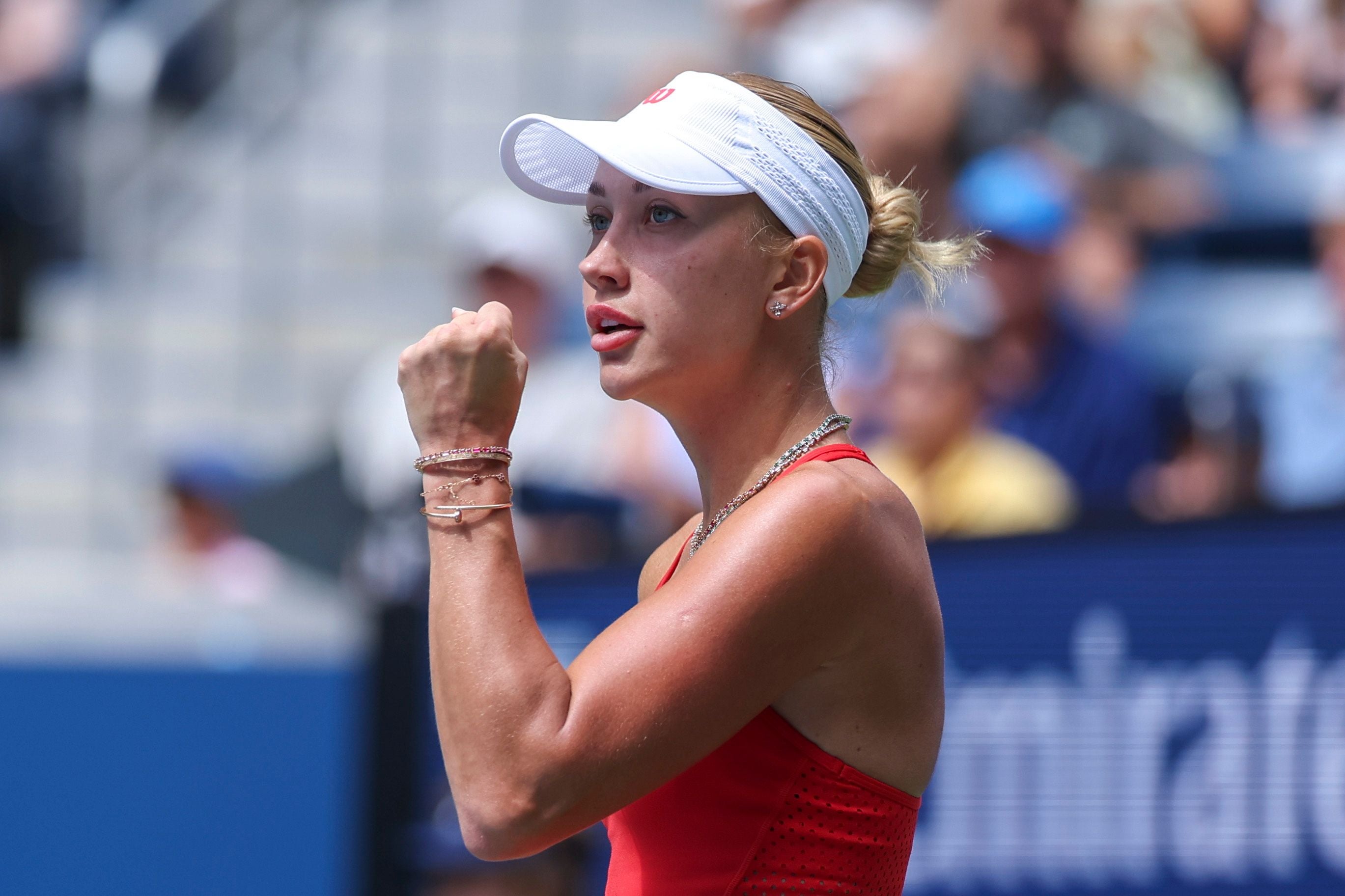 Tennisspielerin im roten Outfit jubelt mit geballter Faust auf dem Tennisplatz.